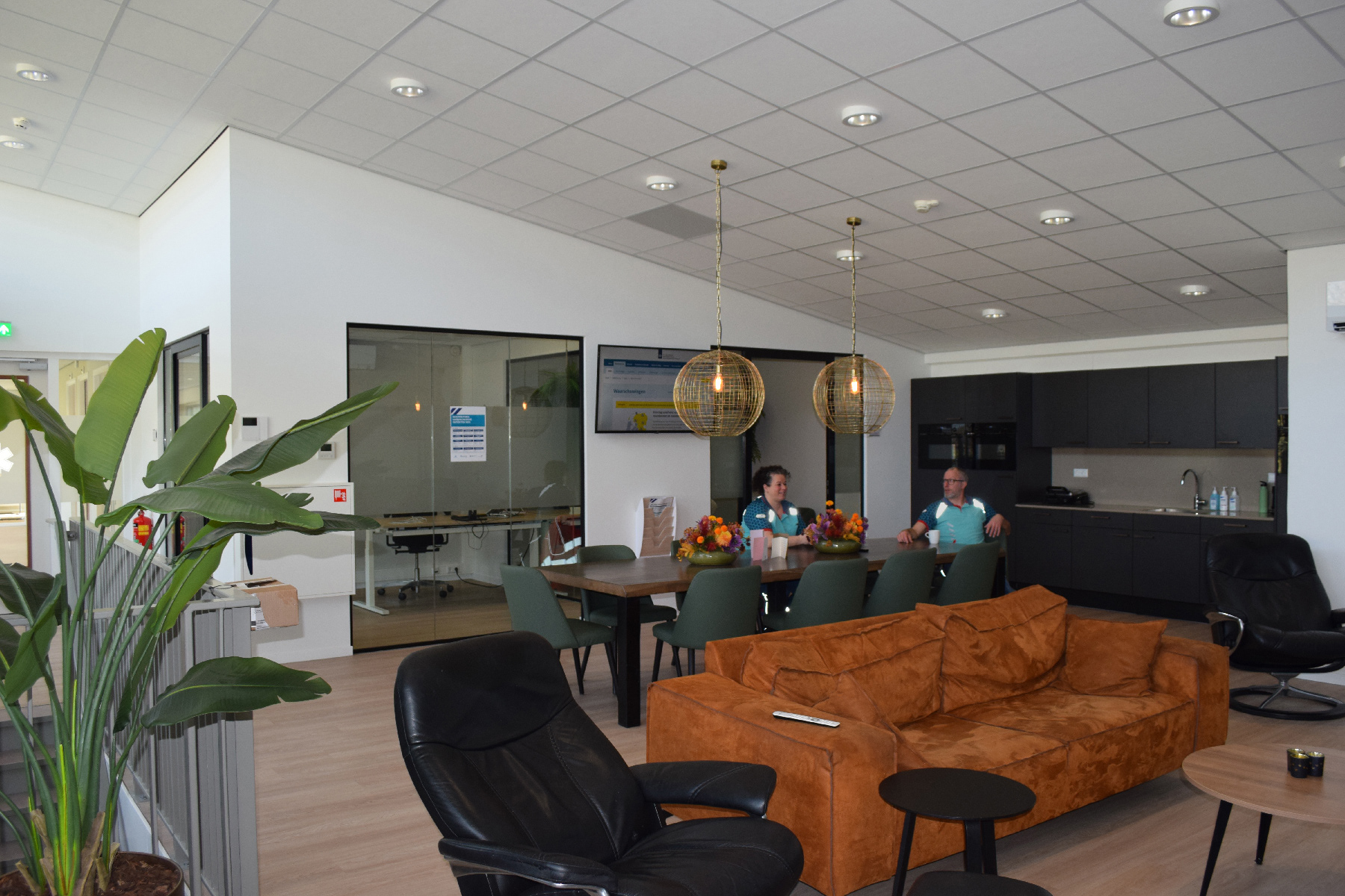 Sociale ruimte met op de achtergrond besloten werkplekken