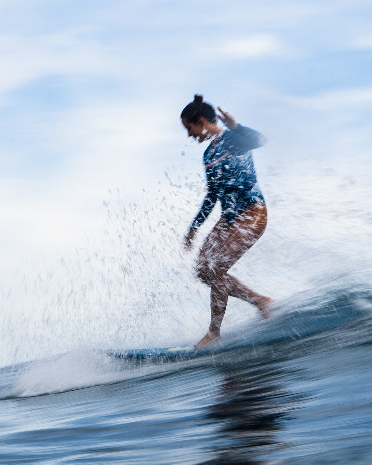 Slow shutter photo of Chloe Calmon riding a longboard in Lombok, Indonesia. Shot from water