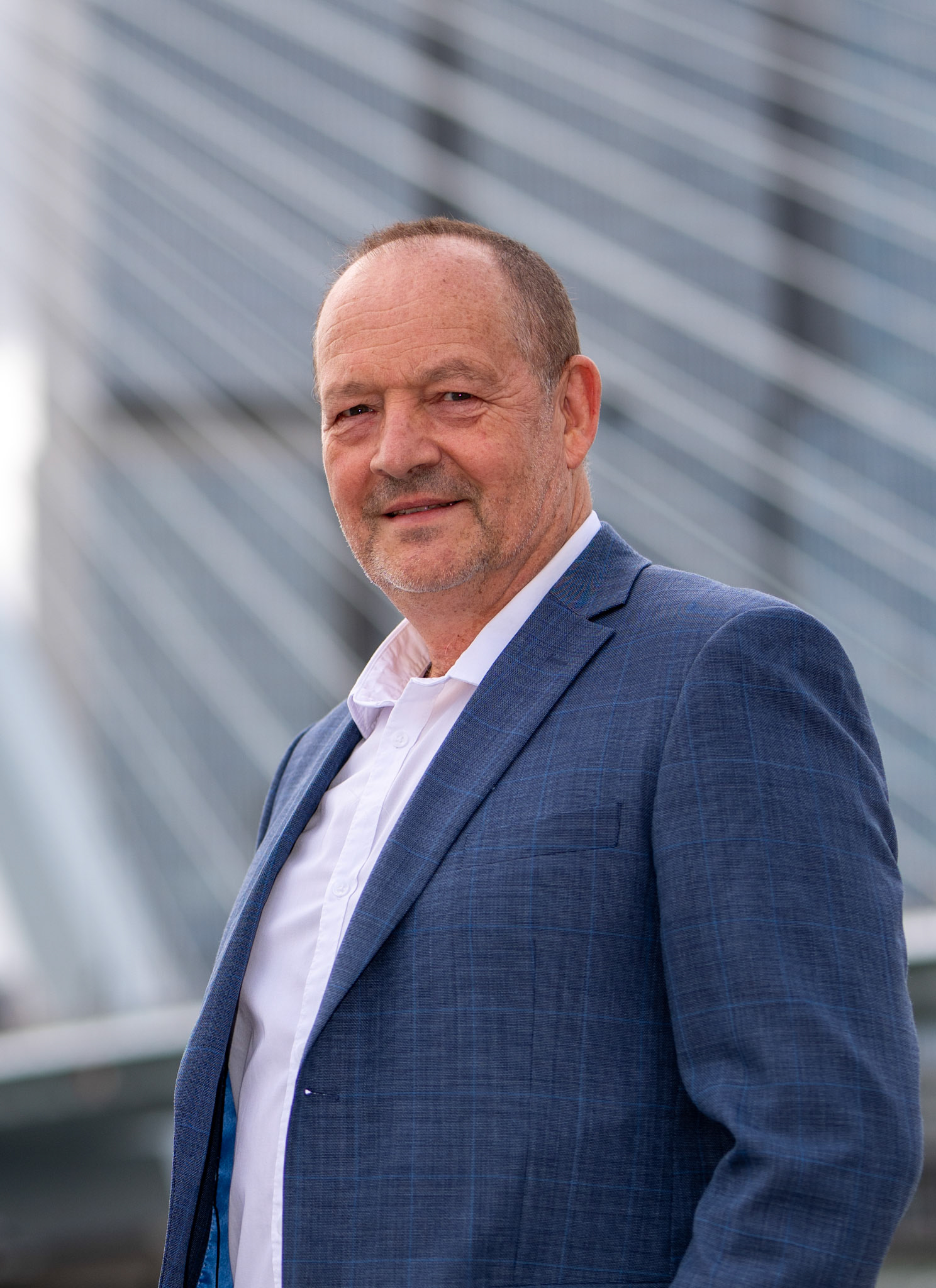 Zakelijk portret man op locatie in Rotterdam centrum met subtiele Erasmusbrug achtergrond.