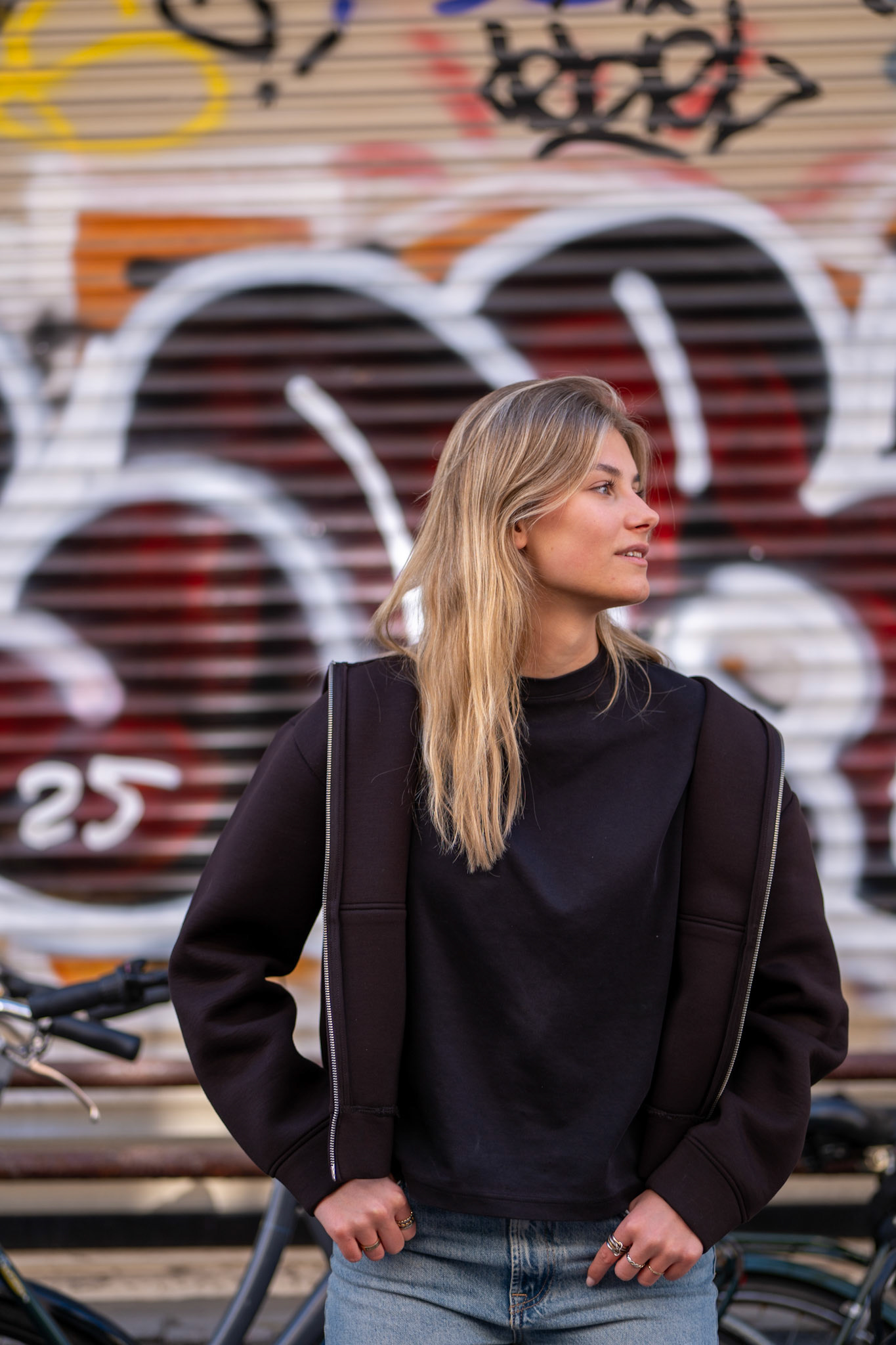Editorial portret van de jonge vrouw Evy, die poseert voor een opvallende, kleurrijke garagedeur in Utrecht. Het contrast tussen haar styling en de levendige kleuren van de deur zorgt voor een dynamisch, grafisch beeld.