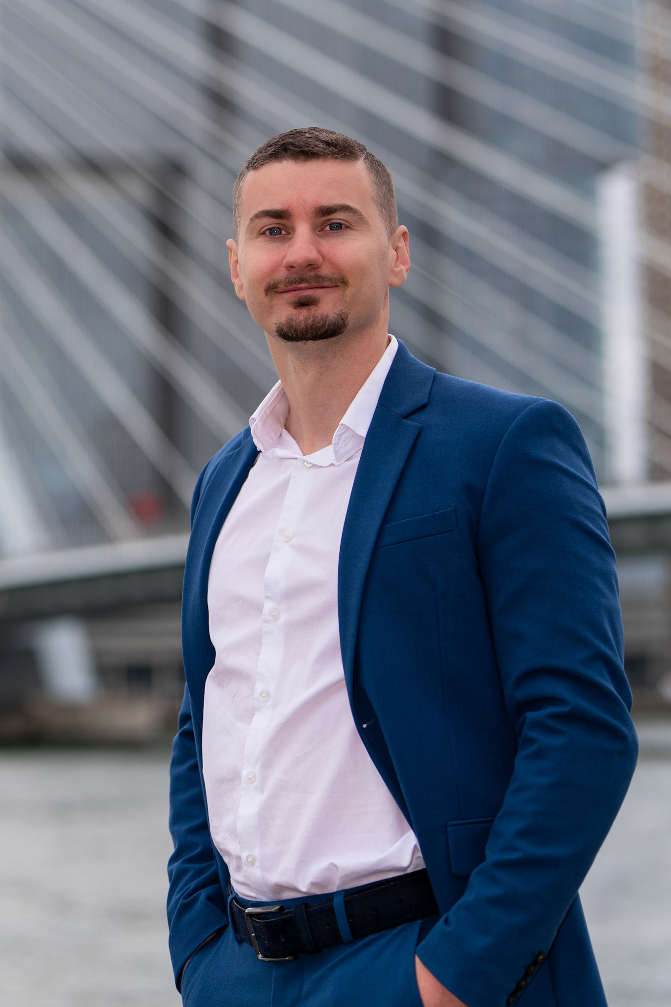 Zakelijk portret man op locatie in Rotterdam centrum met subtiele Erasmusbrug achtergrond.
