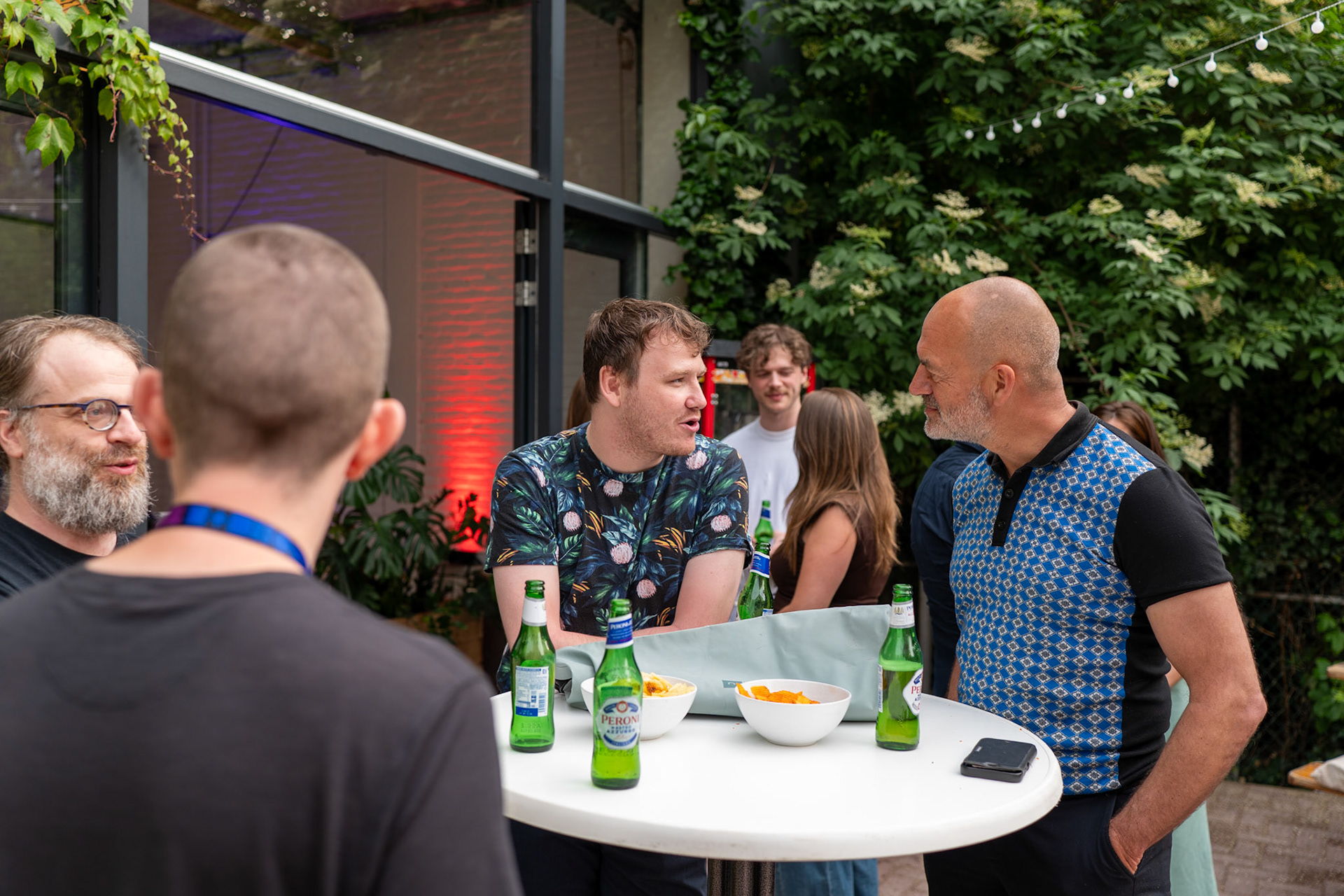 Authentieke evenementenforografie van collega's in gesprek tijdens een zakelijke borrel in Rotterdam, vastgelegd in een cinematic en ongedwongen stijl.