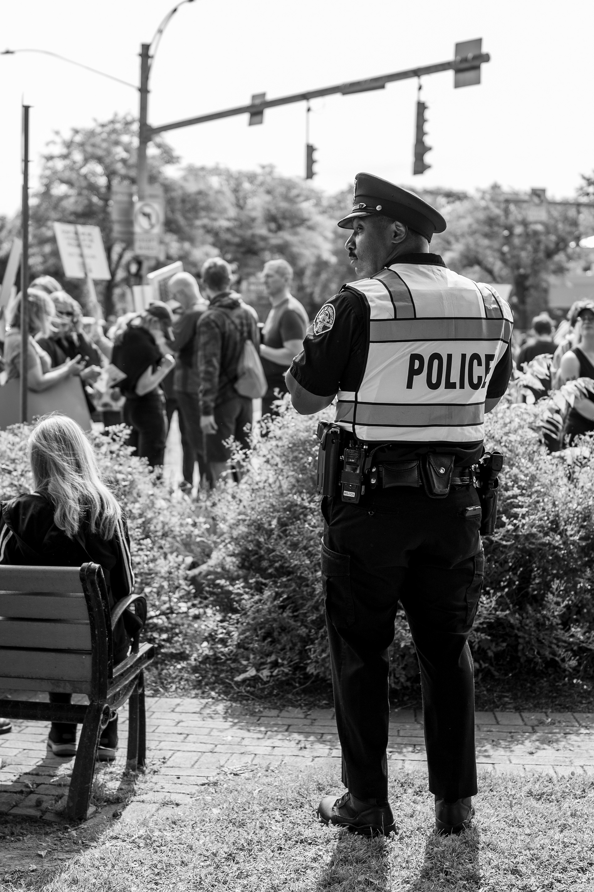 A Brighton police officer watches demonstrators at the Twelve Corners intersection during a No Kings protest in Brighton, N.Y., Saturday, June 14, 2025.
