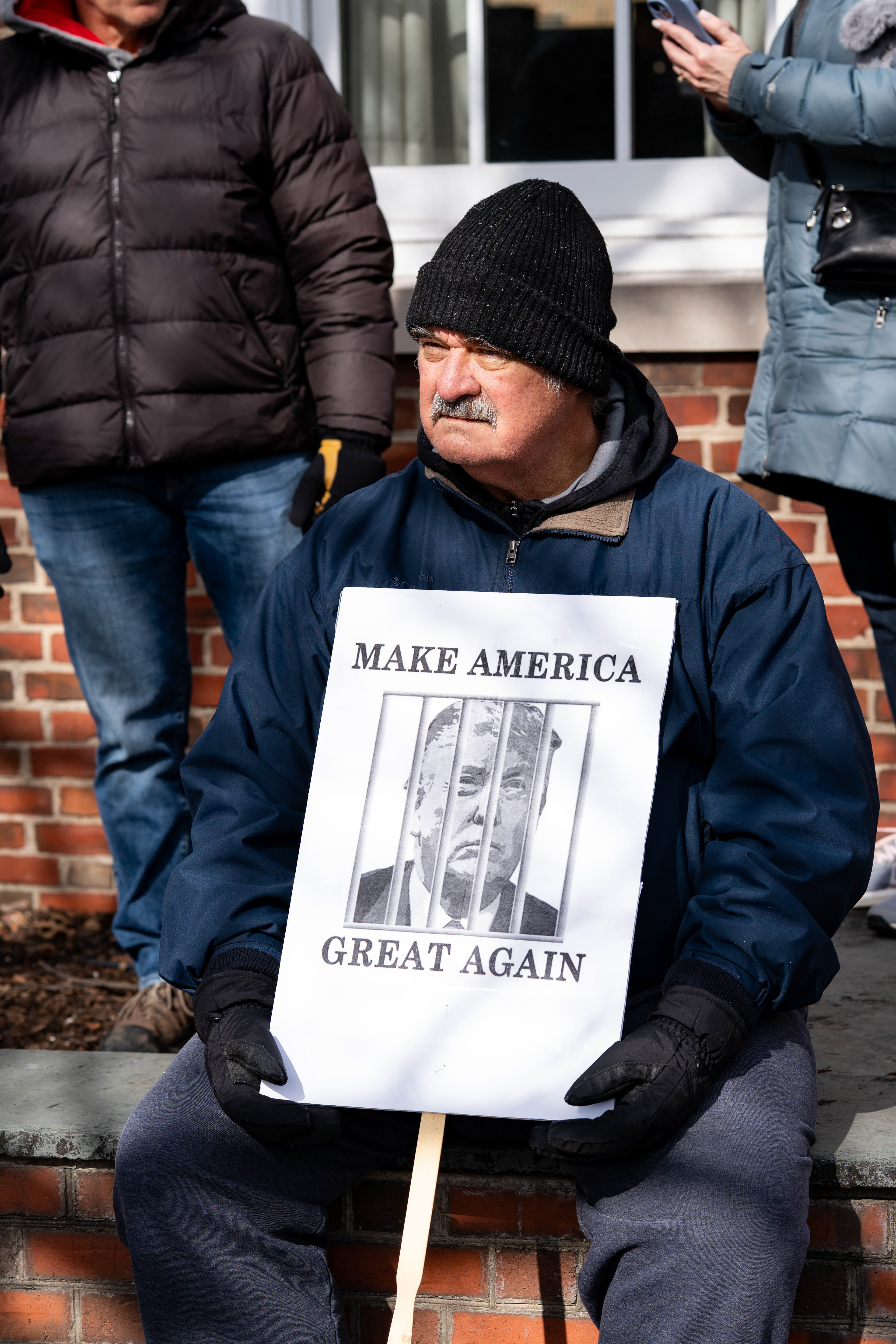 A demonstrator holds a sign showing an image of President Donald Trump behind bars during a No Kings protest in Pittsford, NY on Saturday, March 28, 2026.