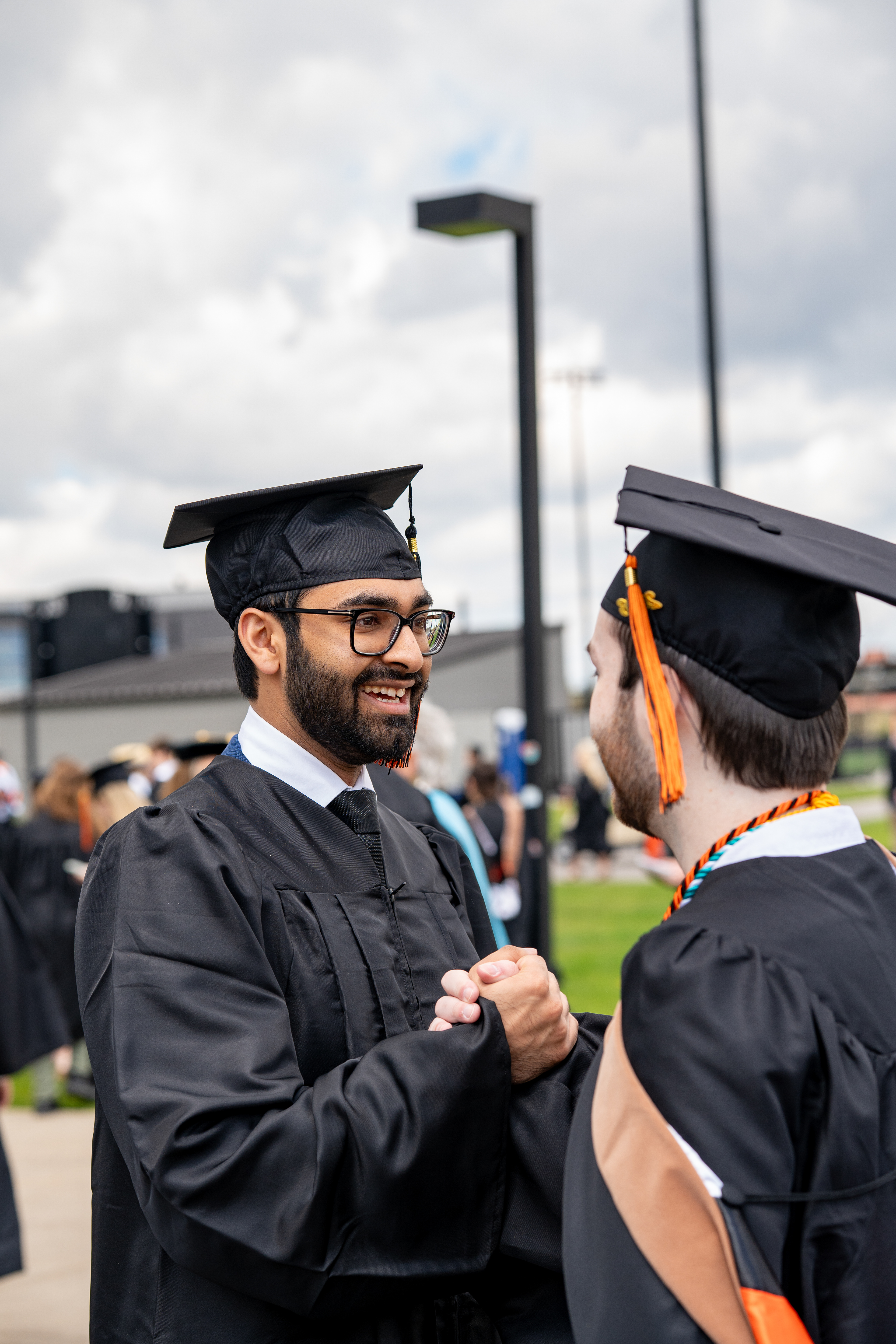 Graduates clasp hands outside the Gordon Field House after the 2026 Academic Convocation at the Rochester Institute of Technology in Henrietta, N.Y., Friday, May 8, 2026.