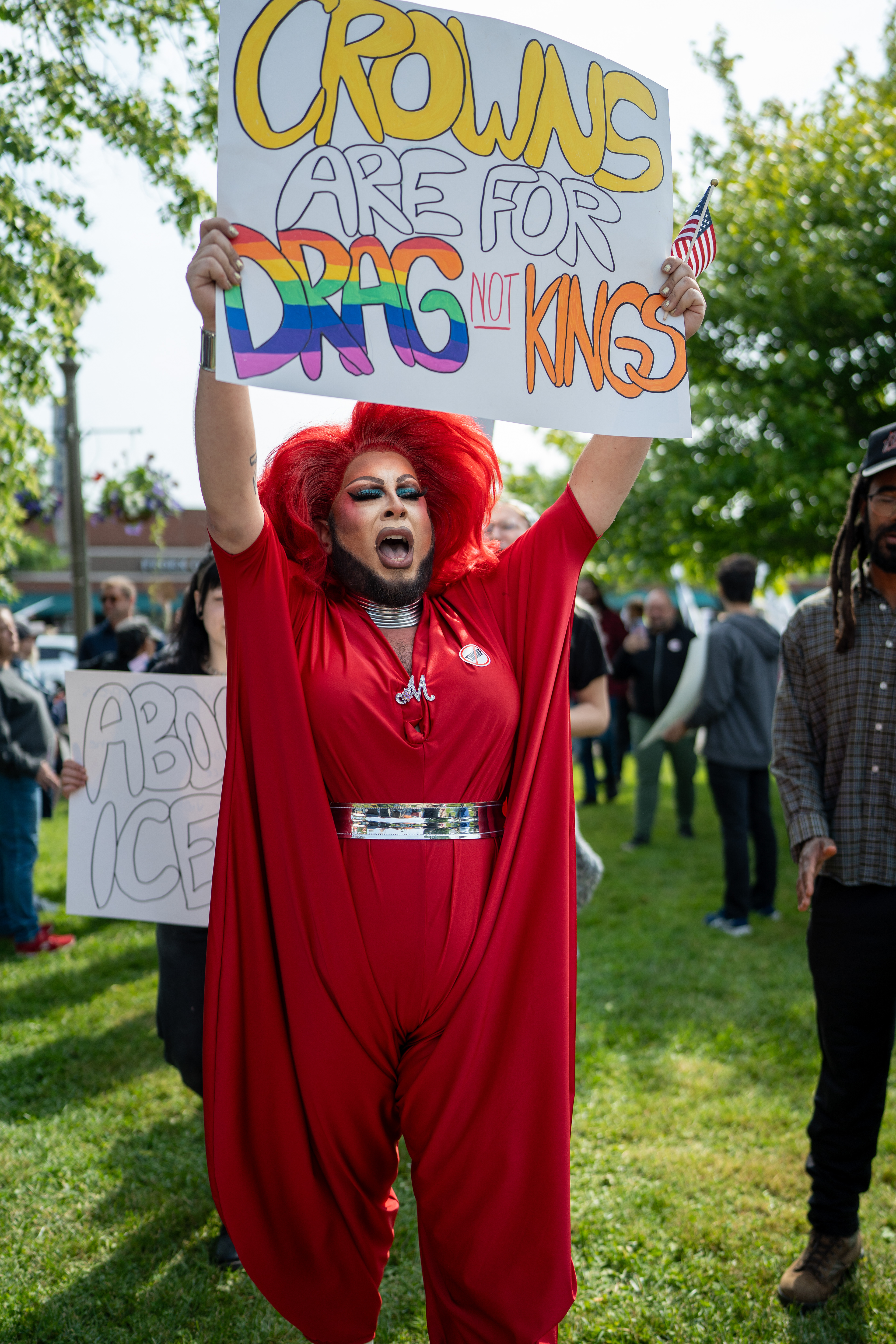 A drag performer shouts while holding up a sign reading “Crowns are for drag, not kings” at the Twelve Corners intersection during a No Kings protest in Brighton, N.Y., Saturday, June 14, 2025.