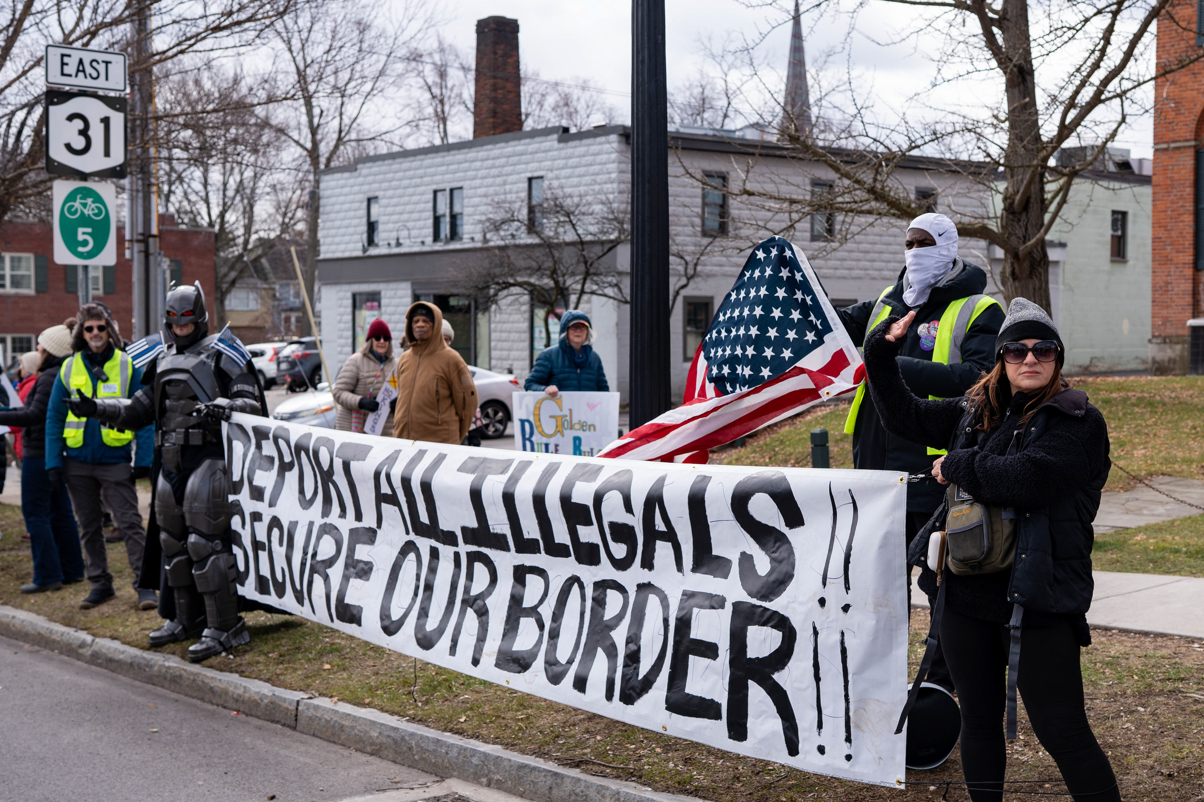 Counterprotesters hold a banner reading “Deport all illegals!! Secure our border!!” during a No Kings protest on North Main Street in Pittsford, N.Y., Saturday, March 28, 2026.