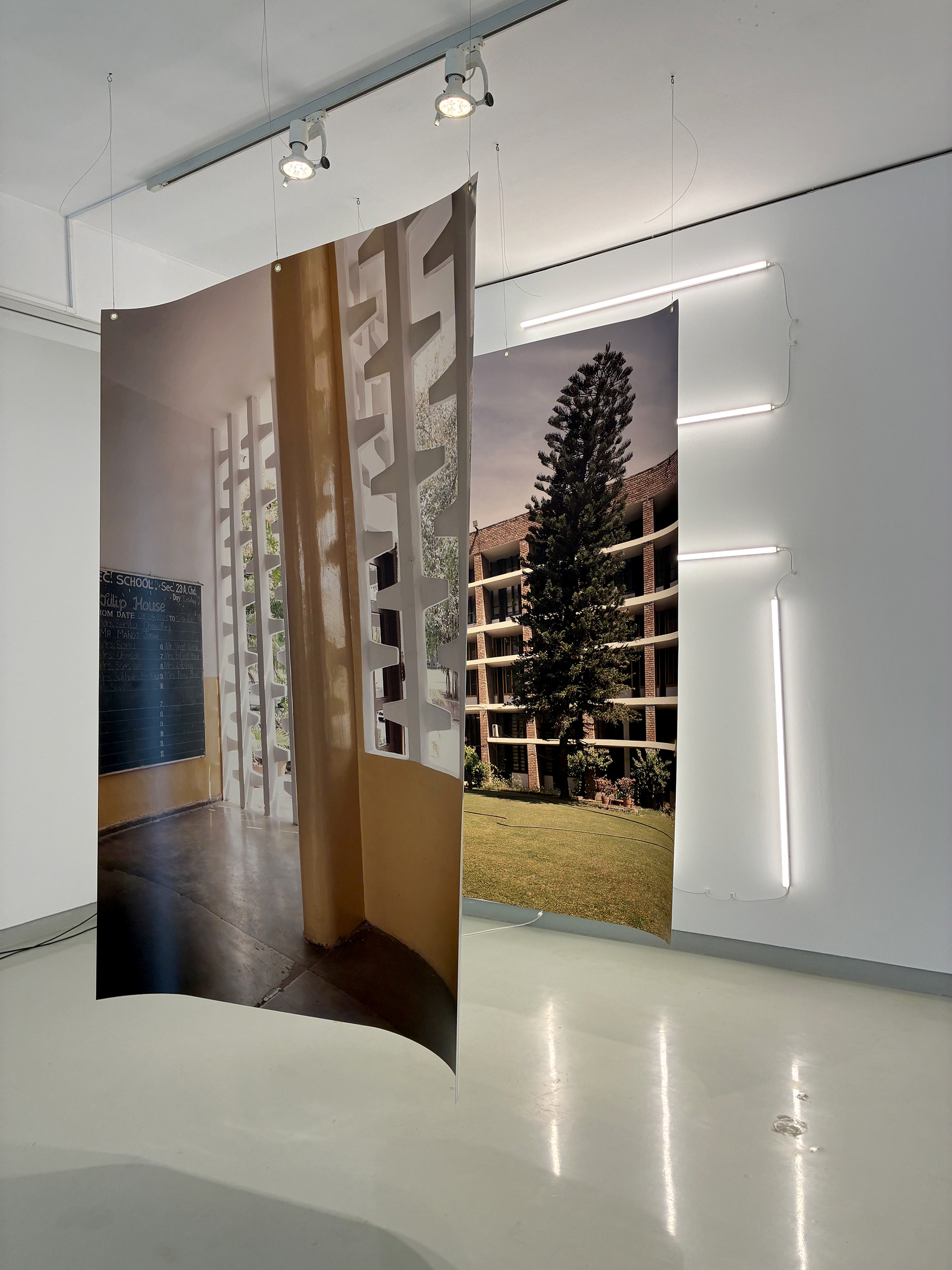 This installation consists of two translucent photographic prints suspended from the ceiling, backlit by six tubular lamps that cast onto the wall a pattern inspired by the jallies designed by Jane Drew for various buildings in Chandigarh. The front image depicts the Government Model Senior Secondary School (Sector 23), designed by Jane Drew; the rear image shows the Women’s Polytechnic College (Sector 10), designed by U. Eulie Chowdhury. The two images deliberately overlap and merge, becoming increasingly difficult to read.  This gesture reflects the way in which women architects have often been obscured in the narrative of modern architecture. Jane Drew, the British architect, appears in the foreground; U. Eulie Chowdhury, the Indian architect, remains partially veiled—echoing the inequalities of visibility that have shaped architectural history.  By bringing these two architects to the centre of the exhibition, Inês d’Orey extends a line of research that has marked her recent work: the investigation, identification, and photography of buildings designed by pioneering women architects of the first half of the 20th century. This gesture seeks not only to revisit the history of architecture, but also to rebalance the way in which that history is told.