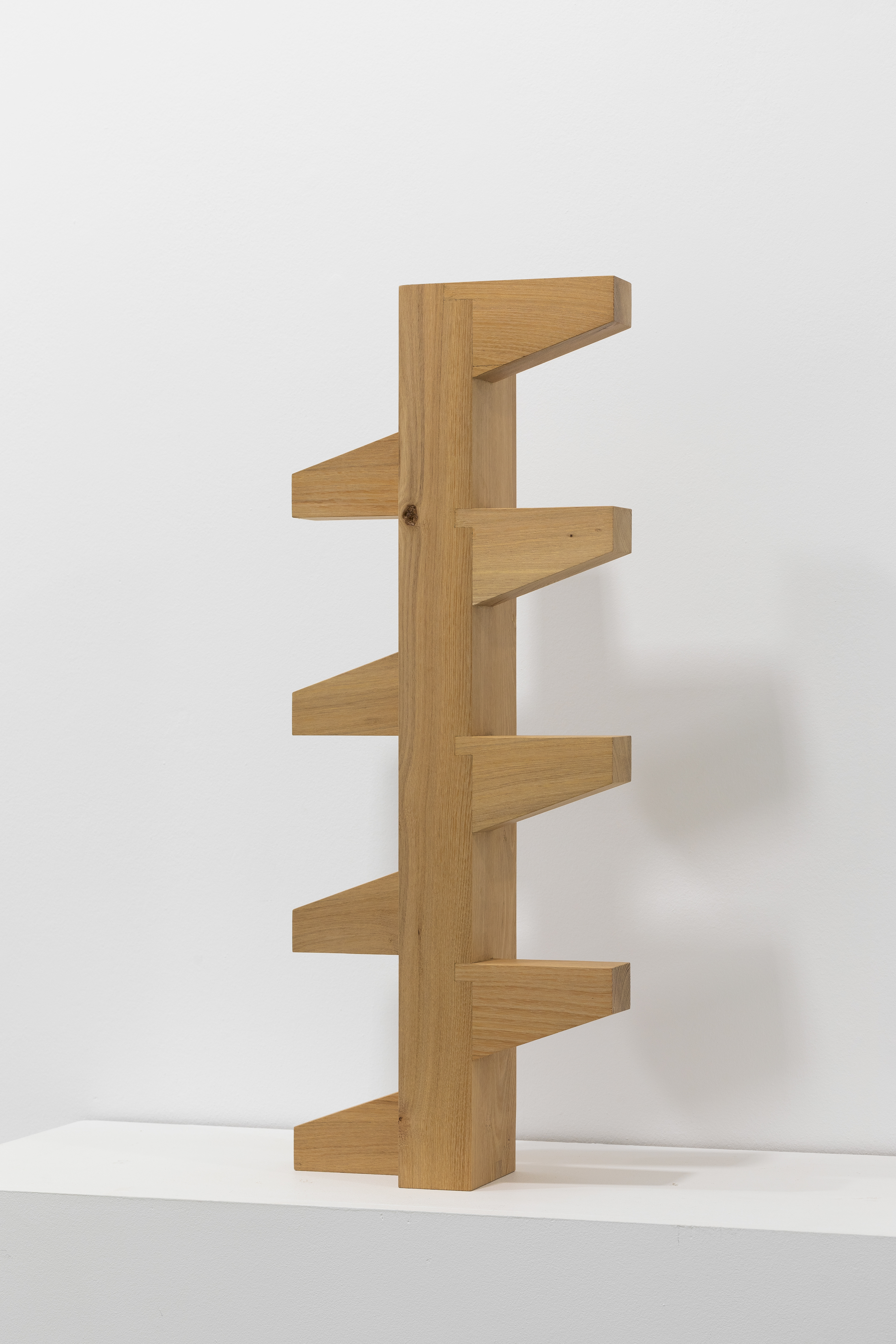 Umbral #3. Sculpture in acacia wood. 74x20x12cm. Edition of 3. The sculptures were designed based on existing modules found in the Sixth Pantheon of Chacarita, serving as a tribute to the work of Ítala Fulvia Villa. Originally made of concrete and integrated into a repetitive pattern of railings or panels, they can be identified in the photographs. They were recreated in acacia wood using Japanese joinery, without a single screw.