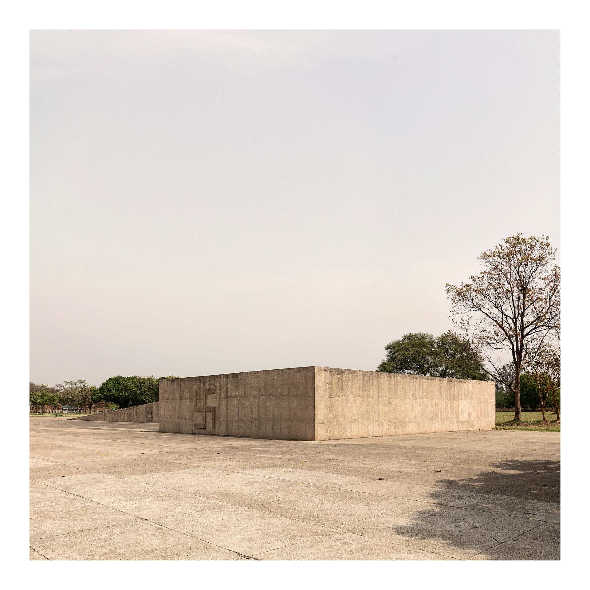 Capitol Complex #2. Fine Art Photographic Inkjet Print 50 x 50 cm. Edition of 3. The Martyrs’ Monument, in the Capitol Complex, was conceived by Le Corbusier as a memorial dedicated to those who died during India’s struggle for independence. Its abstract and austere form is inscribed within the monumental landscape of the complex, evoking memory, sacrifice, and dignity. More than a commemorative monument, it functions as a symbolic space for contemplation at the civic heart of Chandigarh. The symbols engraved on the walls of the Martyrs’ Monument are the Indian dharma wheel and the swastika, a symbol of the seasons or cycles of human life.