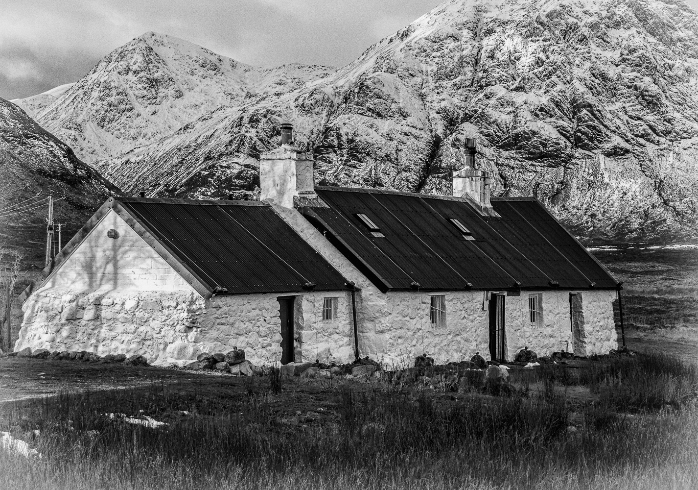 Close up view of Blackrock cottage in November with the snow covered Buachaille Etive Mor in the background