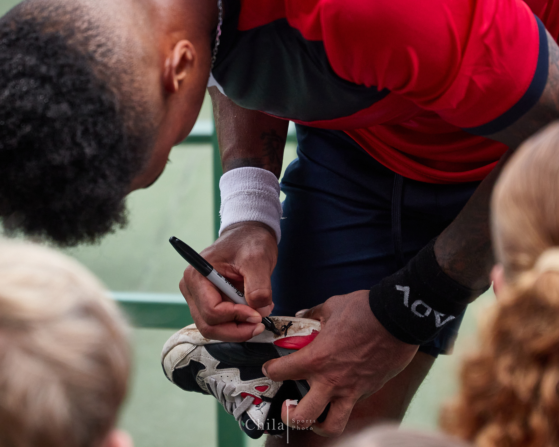 Jessie Flores (CRC) brinda su firma en las tennis de sus jovenes seguidores