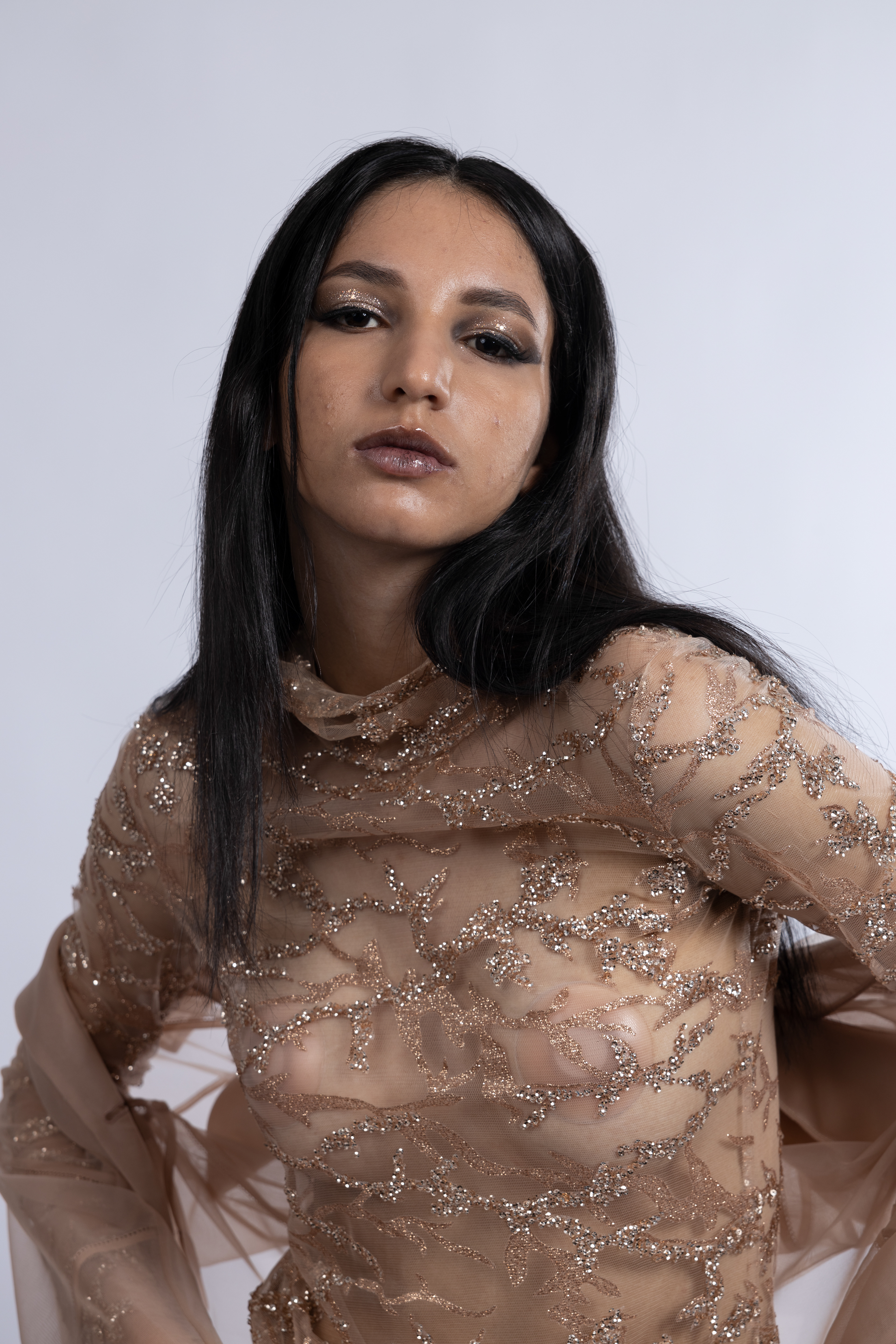 Tipologia: Makeup fashion; Caratteristiche: Smokey eyes allungato e intenso, arricchito da glitter che riprendono i dettagli del vestito per un look armonioso e glamour;  Type: Fashion makeup; Features: Elongated and intense smokey eyes, enhanced with glitter that mirrors the details of the outfit, creating a harmonious and glamorous look;  Makeup e hair: Gino Aurora;