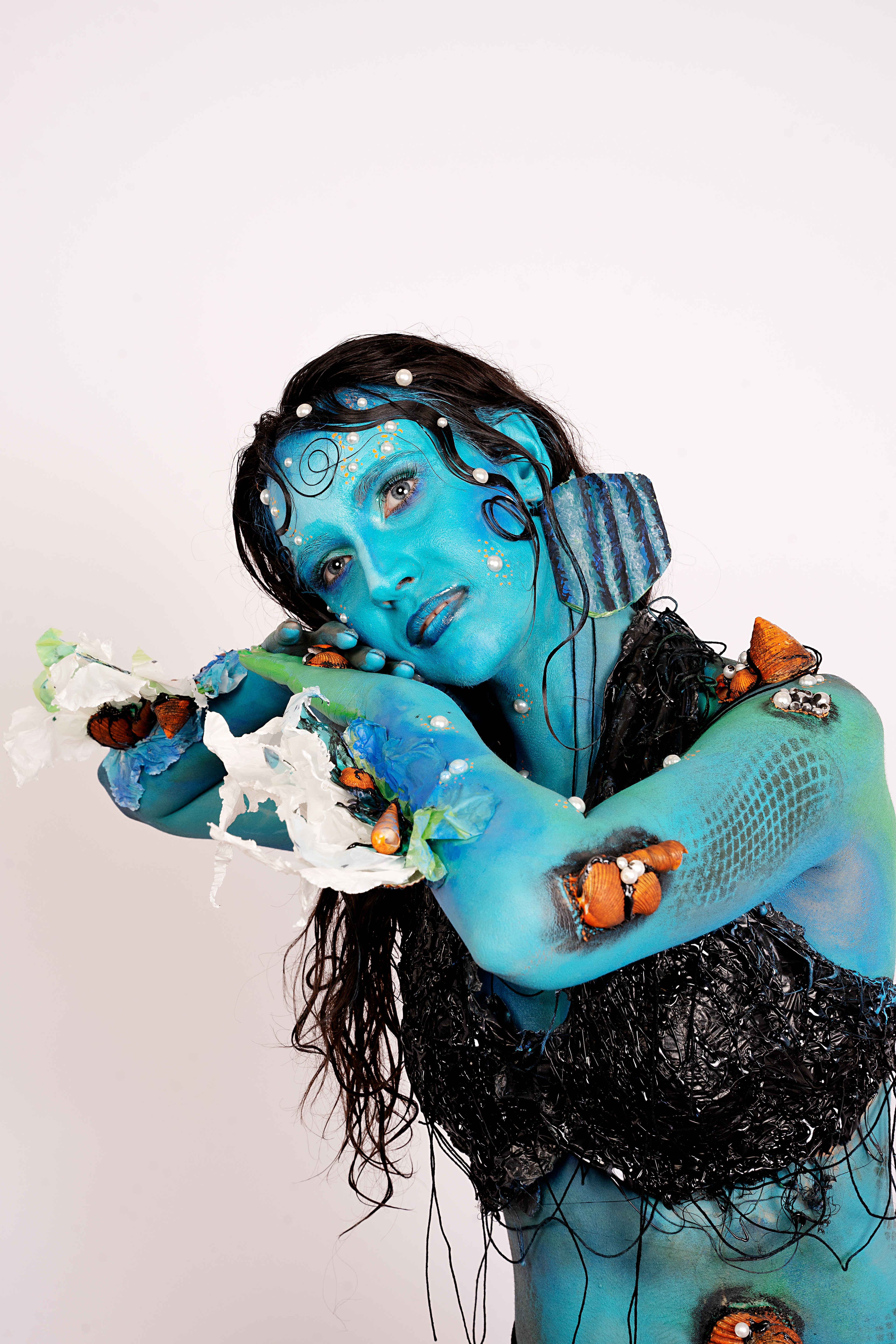 SURVIVED MERMAID Tipologia: Makeup artistico, body painting; Caratteristiche: Il tema di questo progetto è il riciclo. Abbiamo creato una sirena che, per sopravvivere in un mare inquinato, si è fusa con i materiali circostanti, come la plastica. Sono state utilizzate diverse tecniche di bodypainting e makeup artistico. Tutti gli elementi accessori, come pinne, branchie e top, sono stati realizzati utilizzando materiali di scarto; Type: Artistic makeup, body painting; Features: The theme of this project is recycling. We designed a mermaid who, to survive in a polluted sea, has merged with the materials around her, such as plastic. Various body painting and artistic makeup techniques were employed. All accessory elements, including fins, gills, and the top, were made using recycled materials; Makeup hair accessories: Gino Aurora;