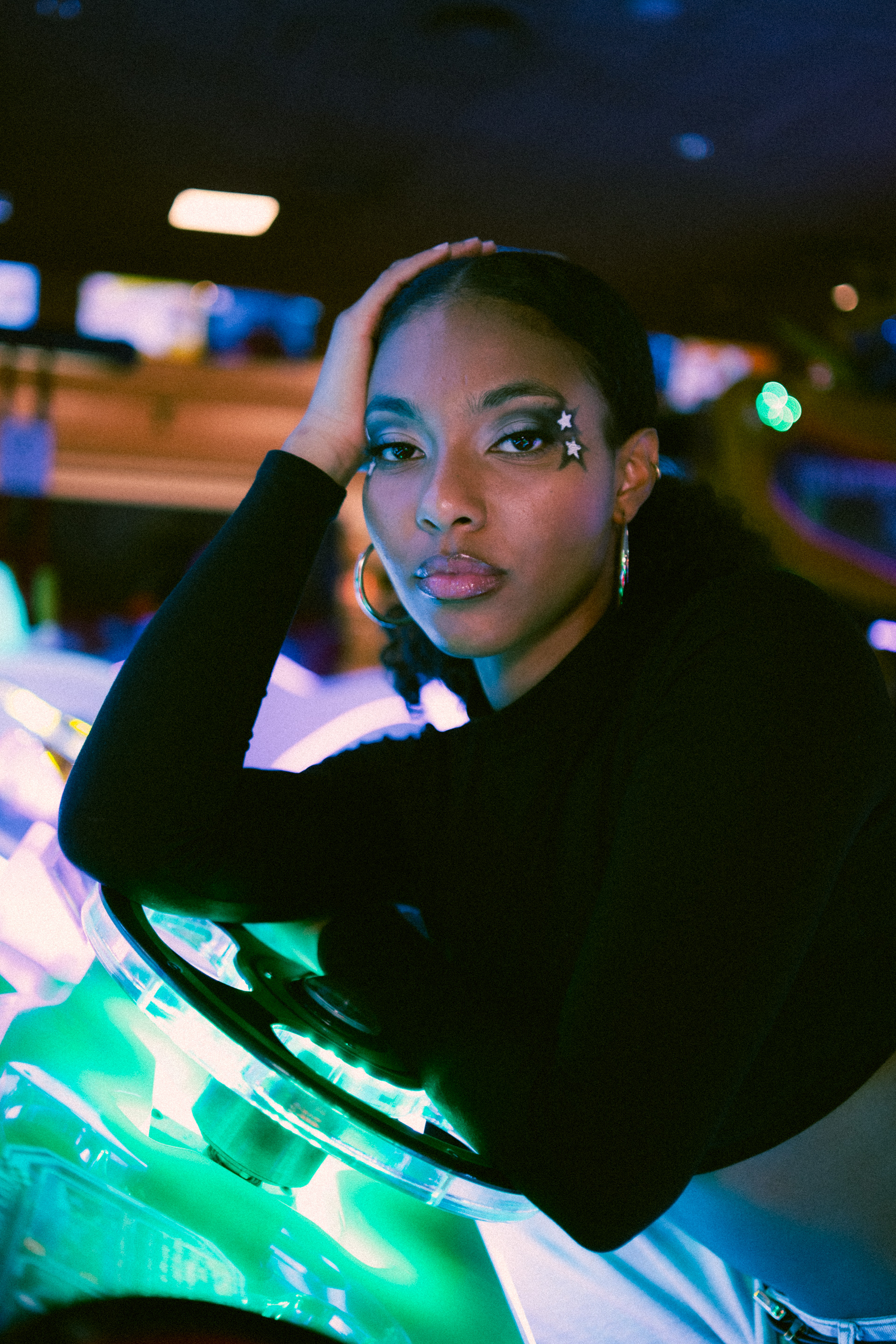 Y2K Arcade Tipologia: Makeup editoriale, artistico;  Caratteristiche:Makeup fortemente ispirato agli anni 2000, caratterizzato da stelle luminose che contrastano con la pelle della modella. Le labbra richiamano chiaramente la moda dei primi anni 2000; Type: Editorial, artistic makeup; Features: A makeup look heavily inspired by the 2000s, featuring bright stars that contrast with the model’s skin. The lips are a clear reference to early 2000s fashion;