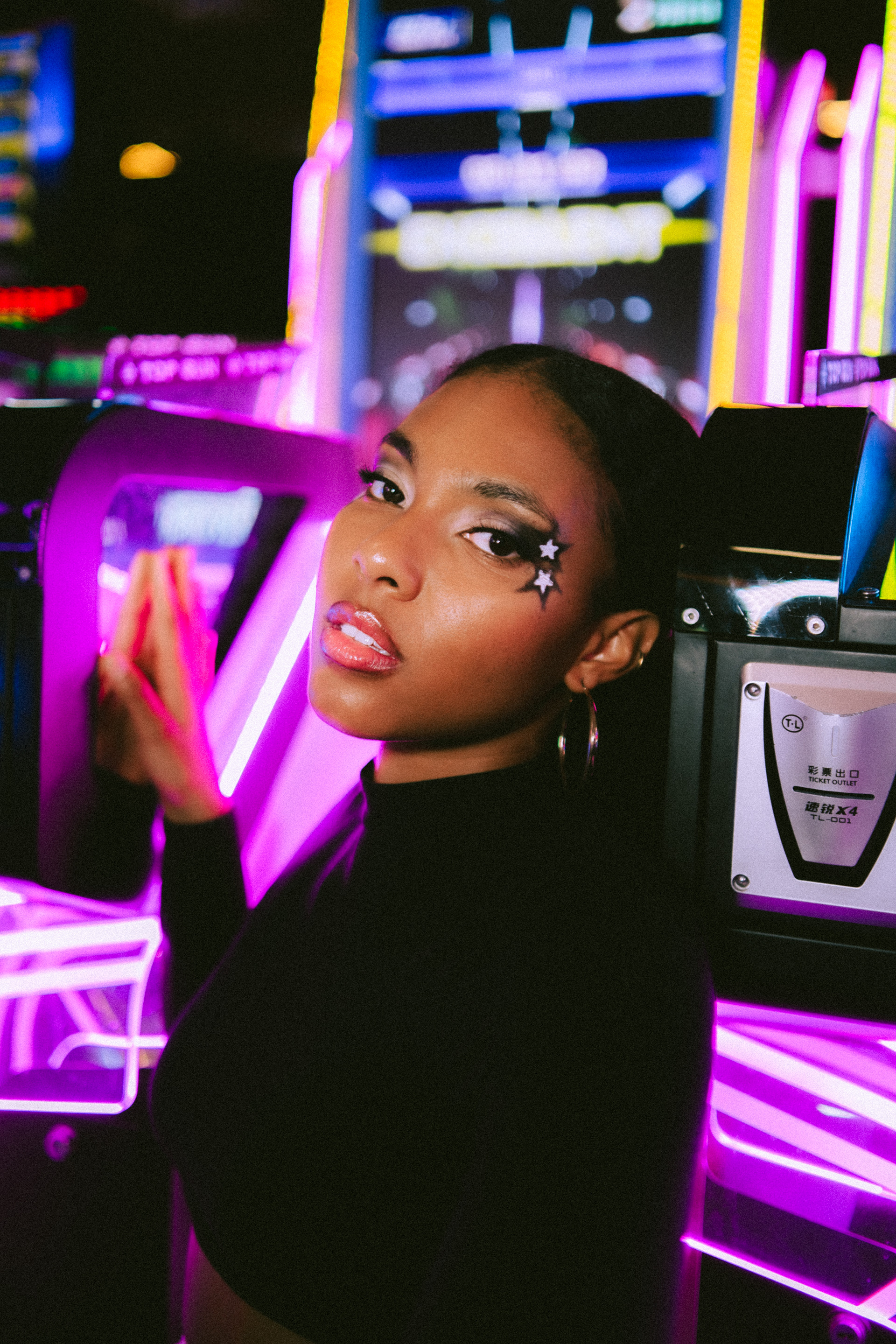 Y2K Arcade Tipologia: Makeup editoriale, artistico;  Caratteristiche:Makeup fortemente ispirato agli anni 2000, caratterizzato da stelle luminose che contrastano con la pelle della modella. Le labbra richiamano chiaramente la moda dei primi anni 2000; Type: Editorial, artistic makeup; Features: A makeup look heavily inspired by the 2000s, featuring bright stars that contrast with the model’s skin. The lips are a clear reference to early 2000s fashion;