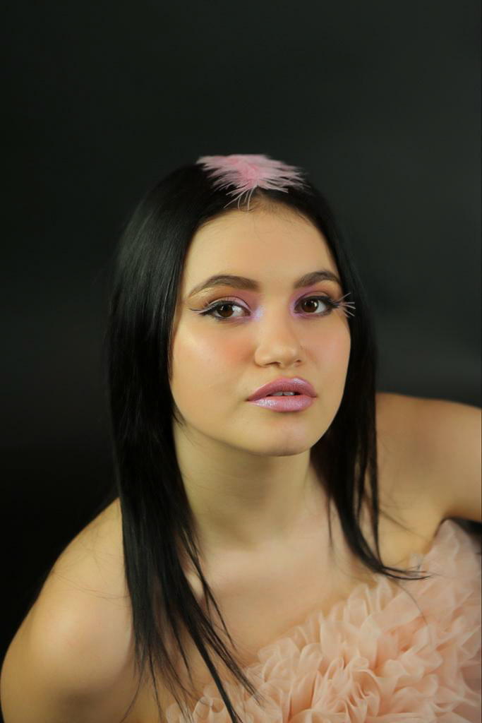 Tipologia: Makeup beauty Soft Glam;  Caratteristiche: Makeup occhi con focus su l'allungamento dello sguardo, arricchito dall'applicazione di piume alla fine degli occhi per creare un effetto elegante e teatrale. Le piume sono state riprese anche nell'acconciatura, creando armonia tra makeup e styling; Type: Makeup beauty Soft Glam; Features: Eye makeup designed to elongate the gaze, enhanced by the addition of feathers at the outer corners for an elegant and theatrical effect. The feathers are also incorporated into the hairstyle, creating harmony between the makeup and styling; Makeup: Gino Aurora;