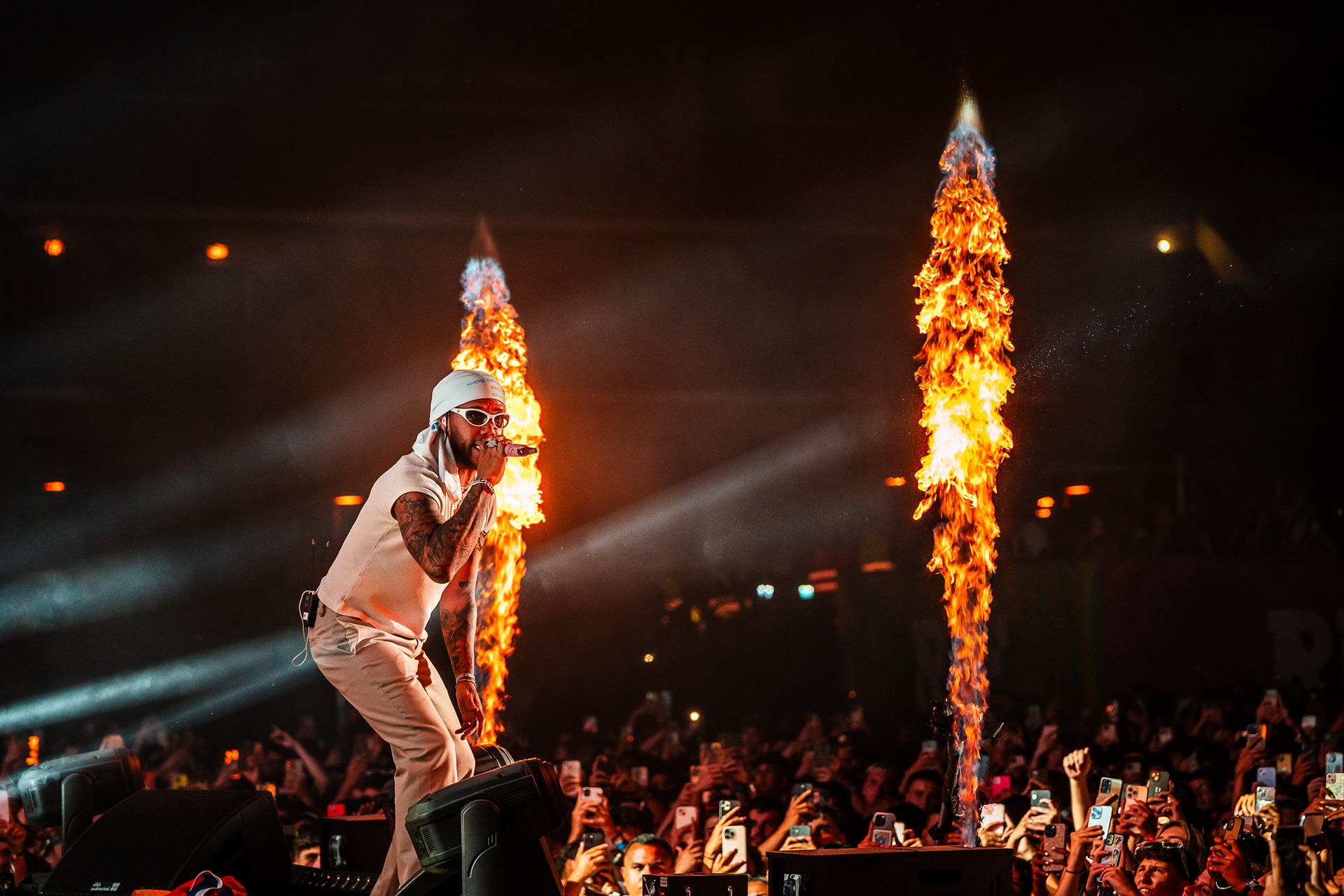 Jhayco (Jhay Cortez) entregando una potente actuación de reggaetón en el Reggaeton Beach Festival Tenerife 2024, con llamas en el escenario y un público entusiasmado.