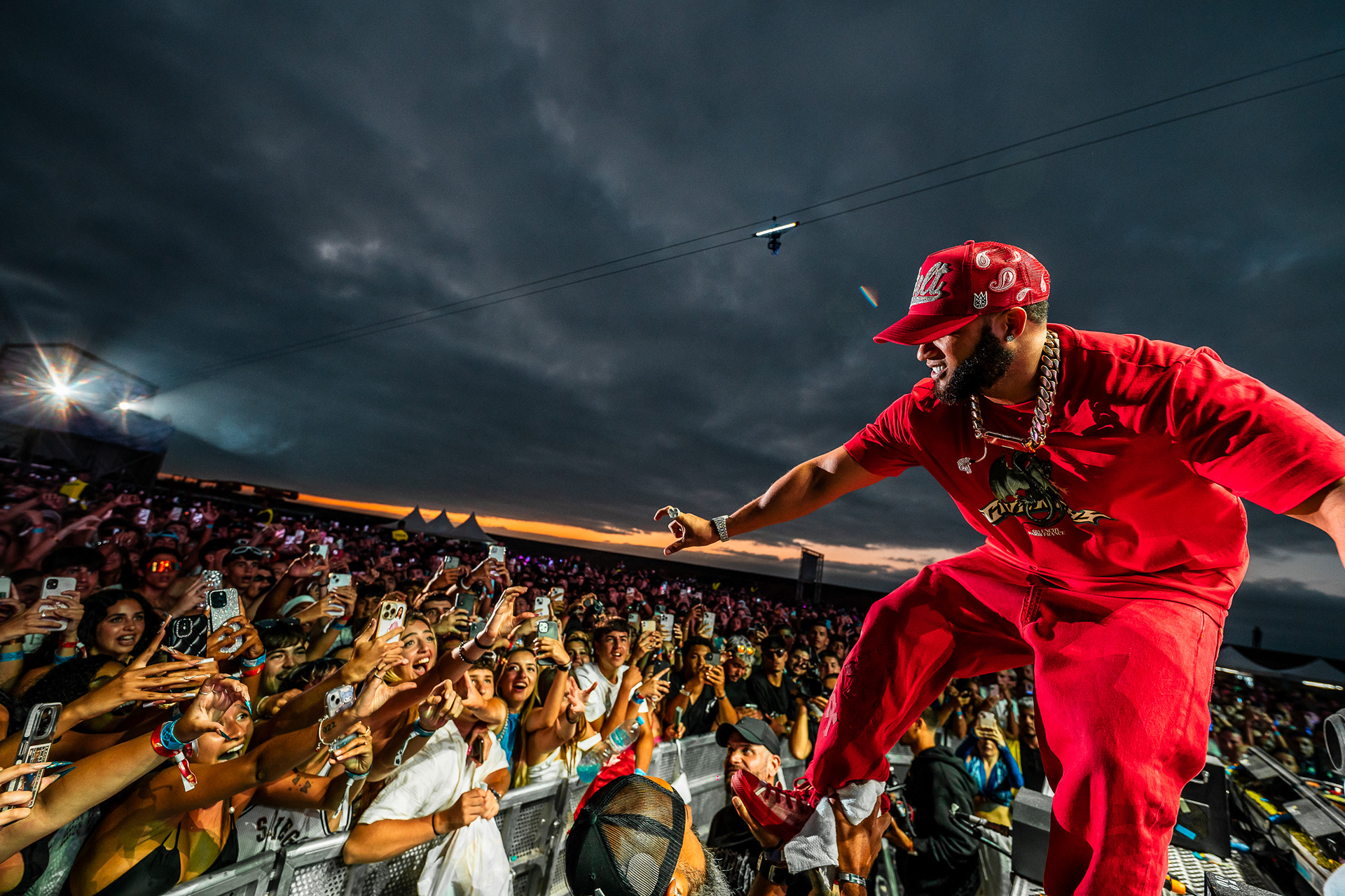 El Alfa, destacado exponente del dembow, interactuando con el público durante su enérgica actuación en el Reggaeton Beach Festival Tenerife 2024, vistiendo un atuendo rojo y recibiendo una ovación en las Islas Canarias