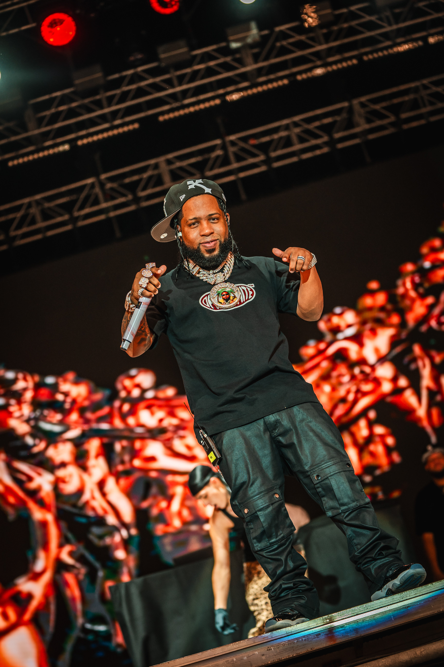 Chimbala, reconocido exponente del dembow dominicano, luciendo un outfit negro y gorra ladeada durante su enérgica actuación en el Cook Music Fest Tenerife 2024, en las Islas Canarias.