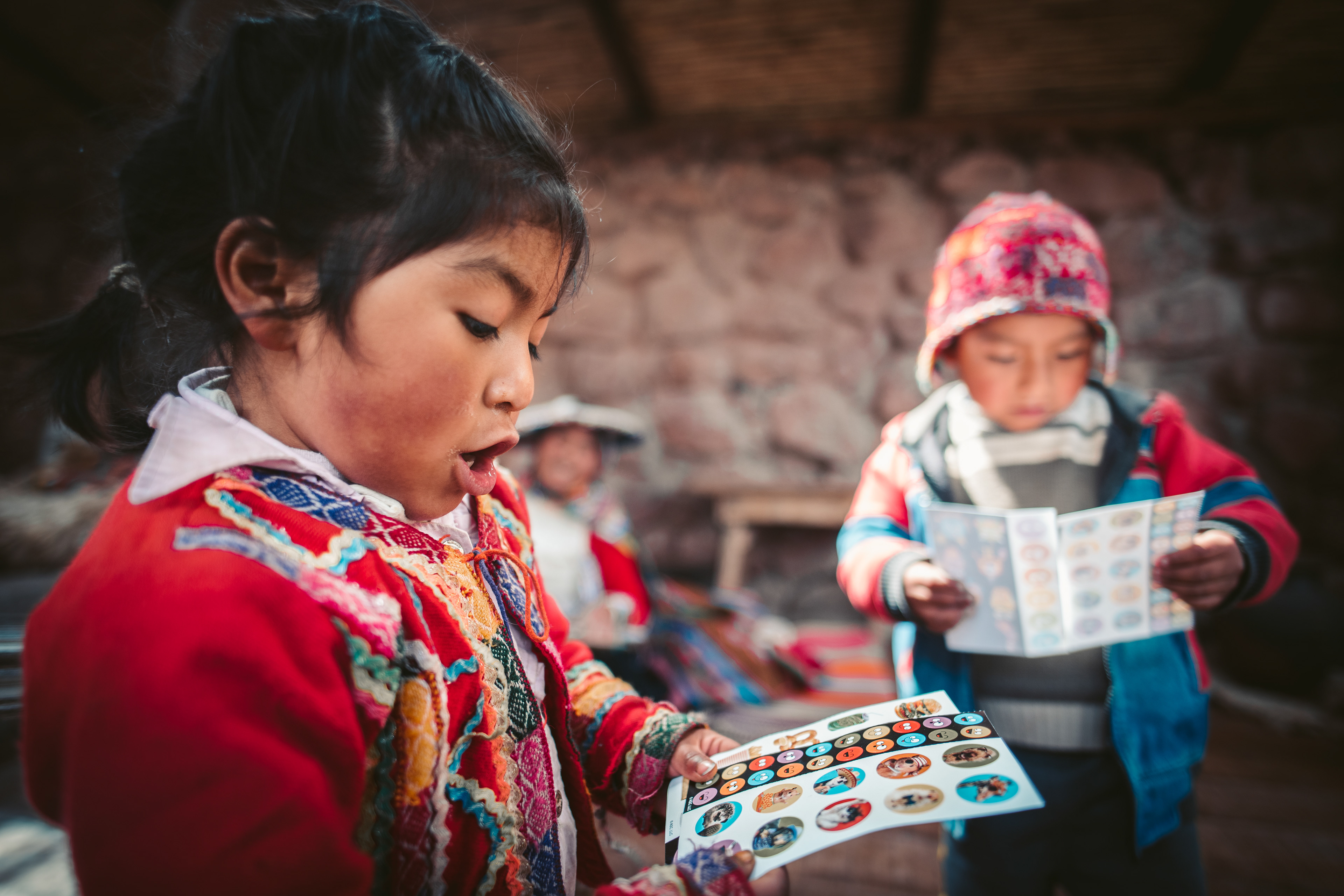 Andean children in Cusco, Peru looking at sheets of stickers I brought for children street vendors
