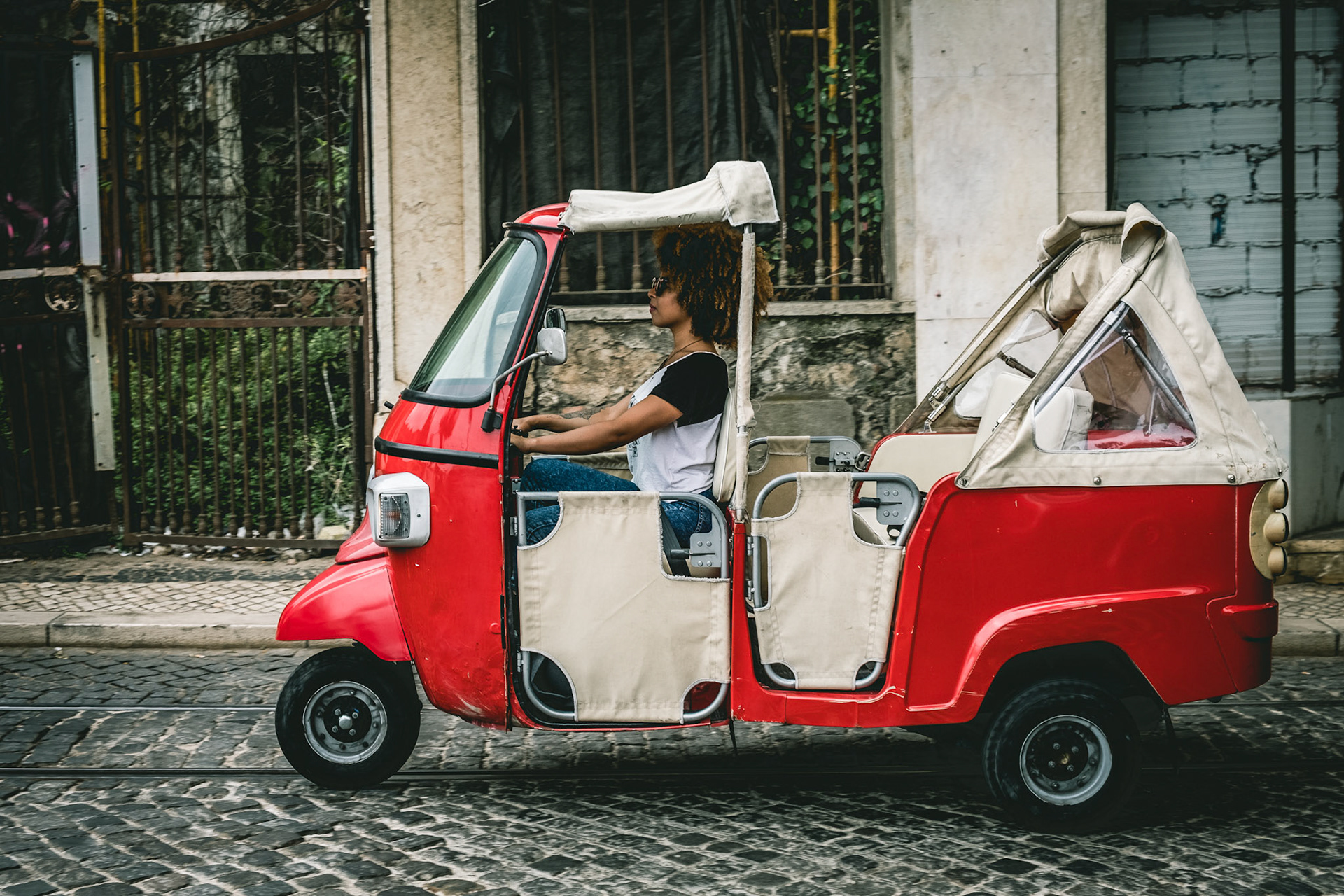 Tourists enjoy a ride in a tuk tuk, three wheeled vehicle in the center of Lisbon, Portugal.