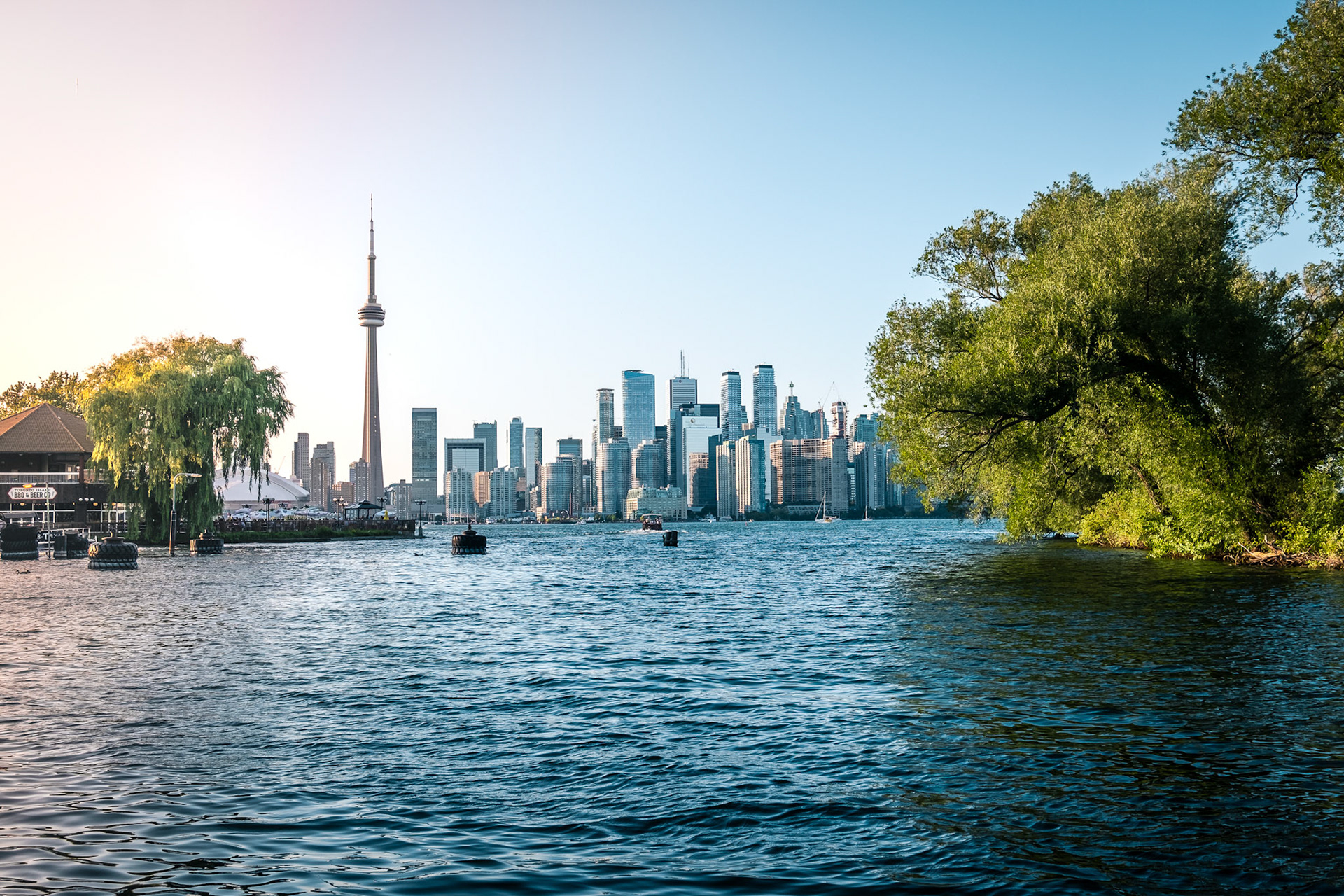 View of CN Tower and Toronto skyline from Toronto Islands Park at sunset.