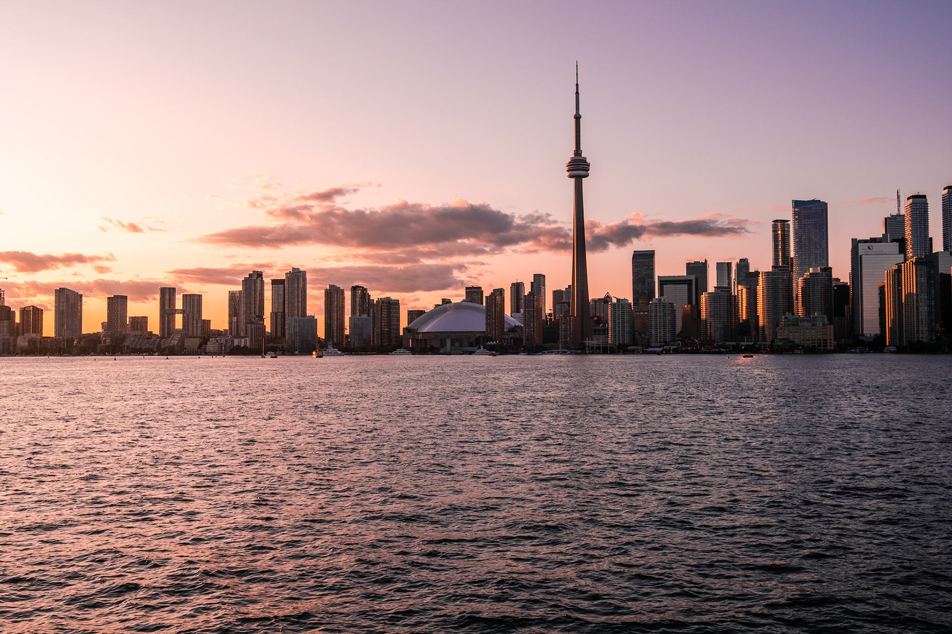 View of CN Tower and Toronto skyline from Toronto Islands Park at sunset.