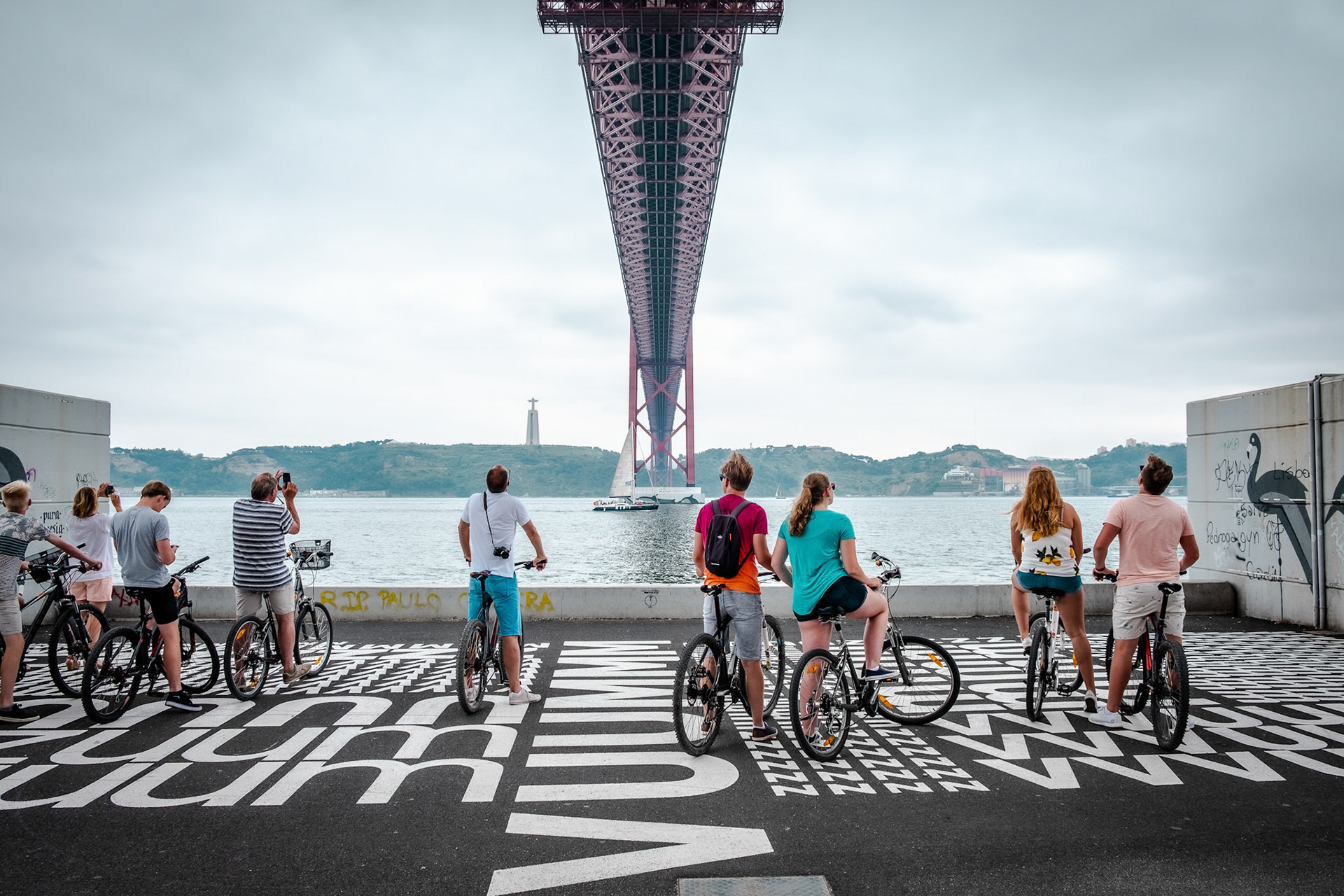 Tourist and locals enjoying the view under the 25 April bridge (Ponte 25 de Abril) is a steel suspension bridge located in Lisbon, Portugal