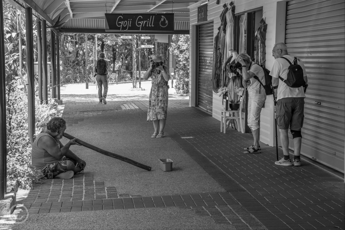 Tourists photographing an aboriginal didgeridoo player, Kuranda, Queensland, Australia