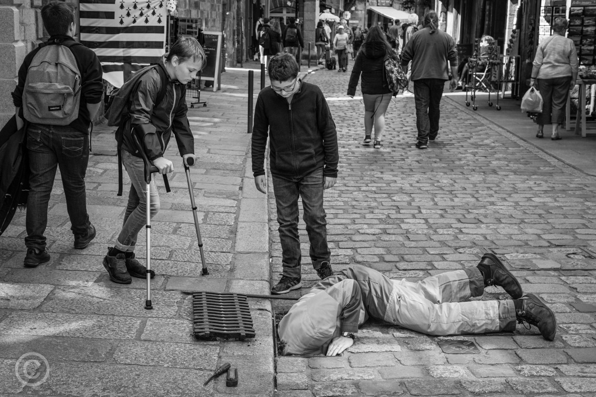 Boys watching a workman in a manhole, Dinan, Brittany