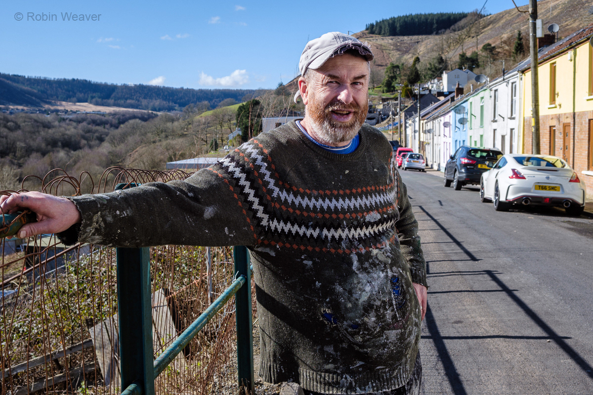 Painter Carl Hughes who has painted many of the colourful houses in the street, 2022