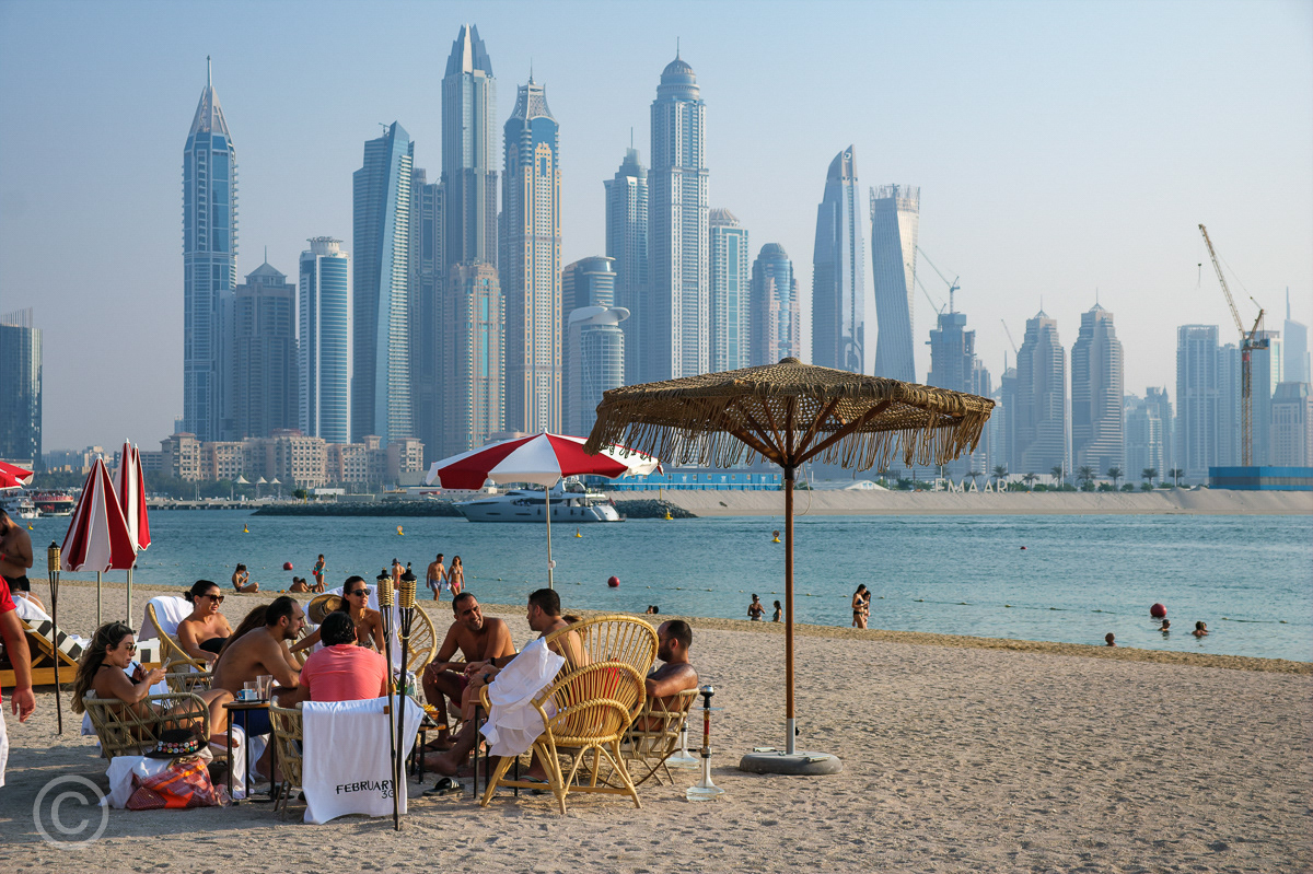 Beach life on The Palm looking towards the skyscrapers at Dubai Marina