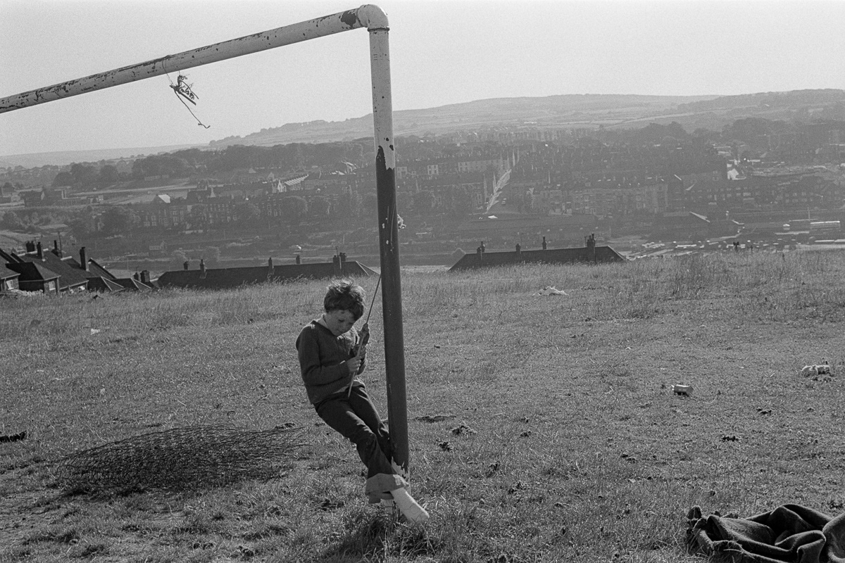 Boy swinging from a goalpost. Whitby, 1976
