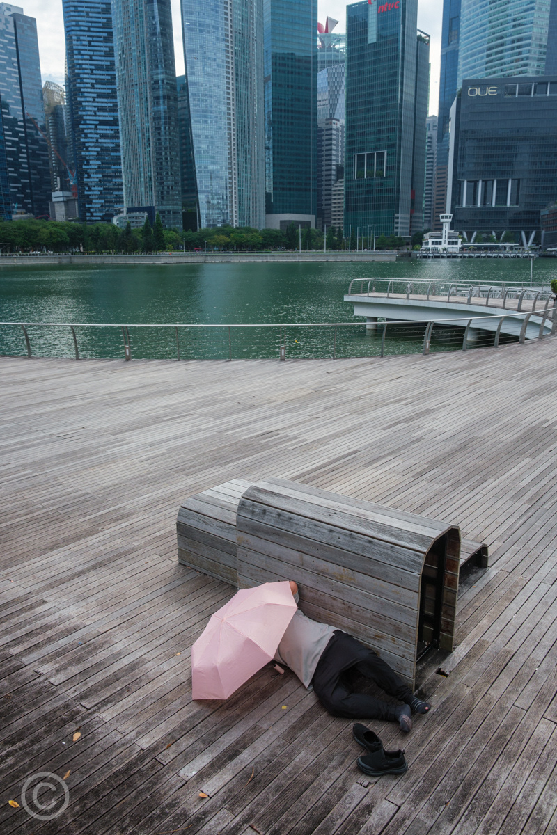 A man sleeping under an umbrella, Marina Bay, Singapore