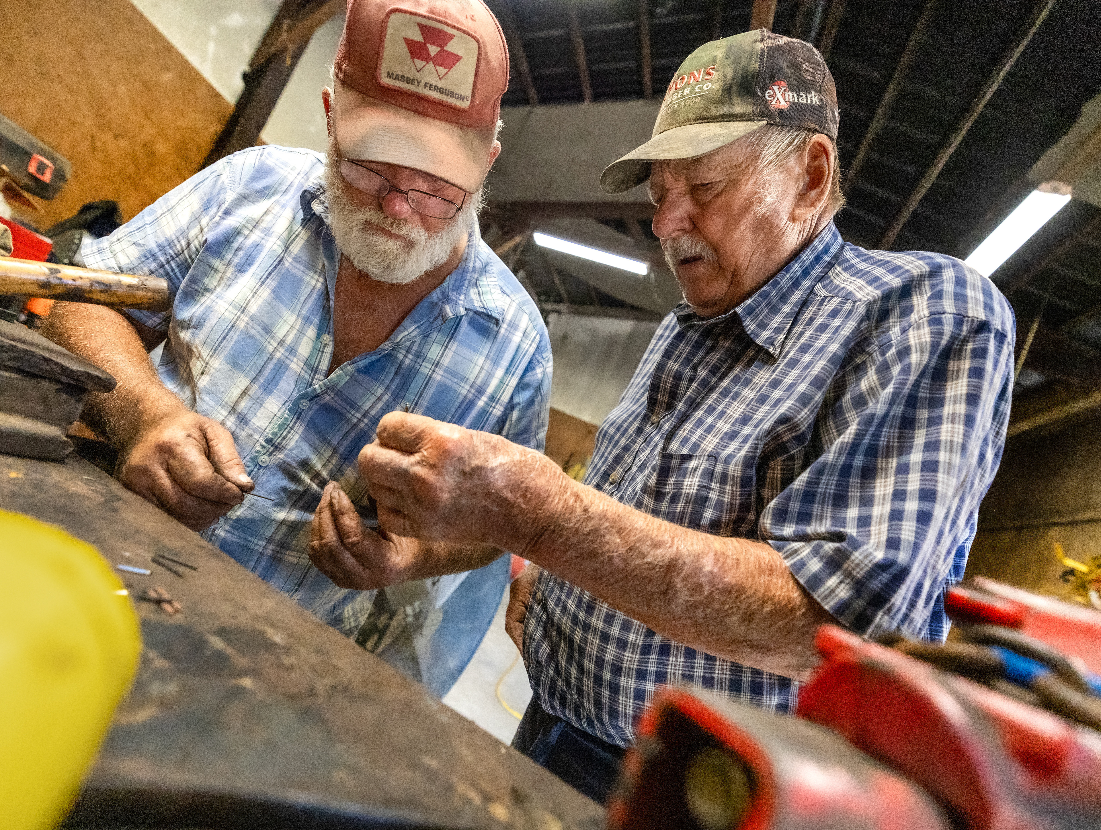 Don Moore, left, and Martin Henson examine a part to a mower on Friday Oct. 13, 2023, in Franklin County, Kentucky. The bush hog they had attached to their trailer had broken down and the two had to fix the part to get back to work. Photo by Matthew Mueller