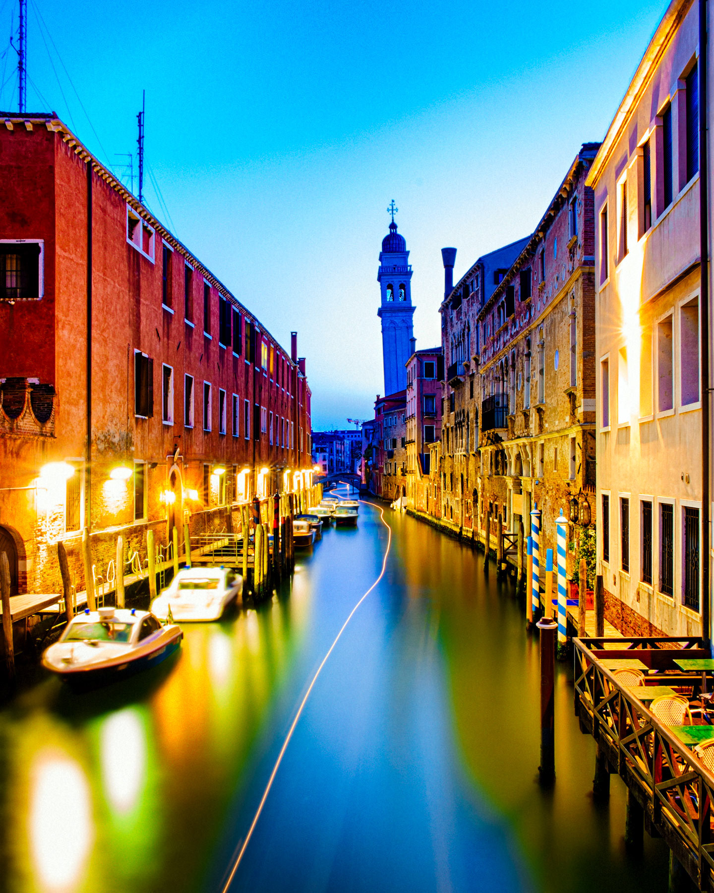 Light trail streaking down Venetian canal at dusk