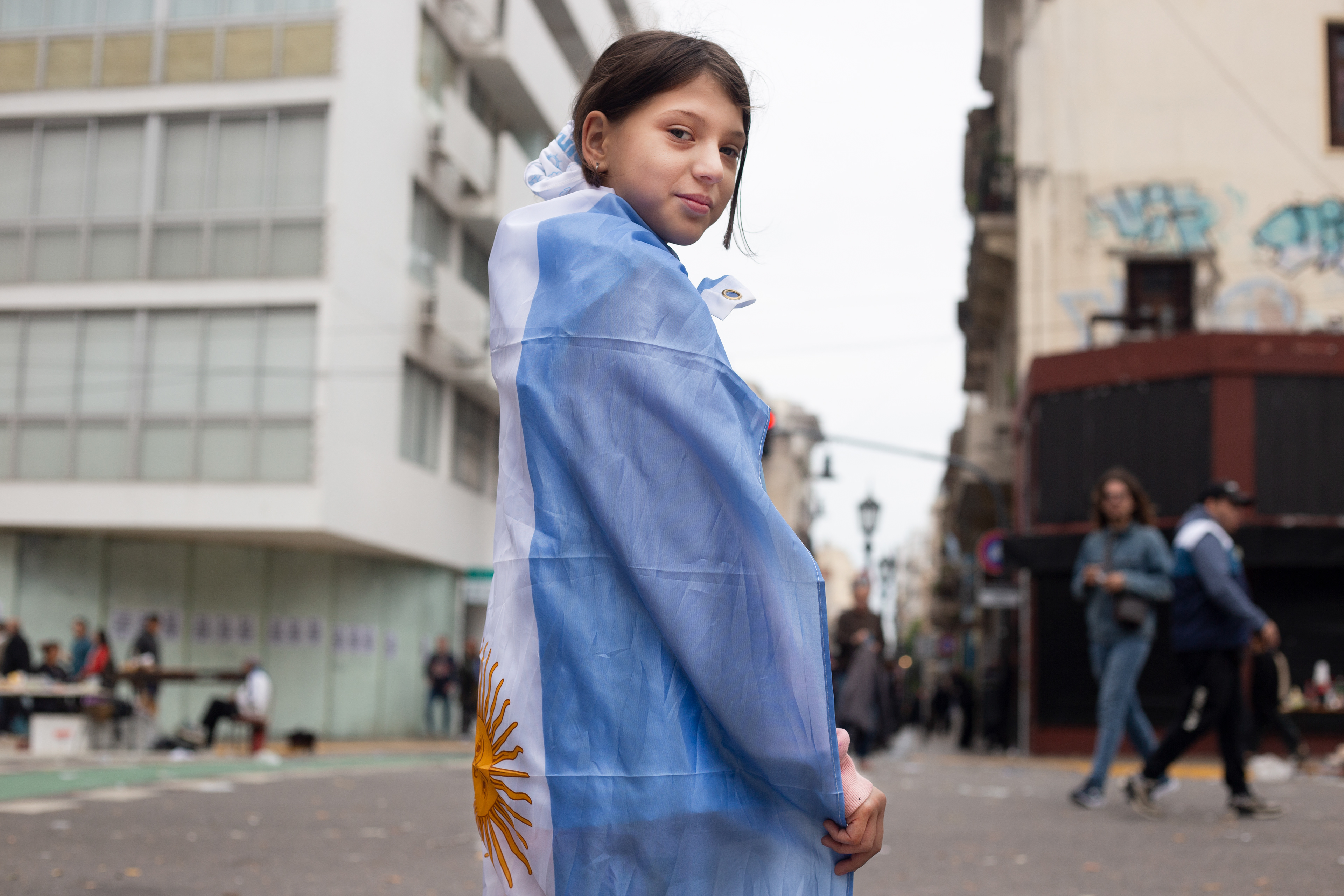 Una nena sostiene la bandera de Argentina en su espalda el 1 de Mayo del Día del Trabajador. Buenos Aires, 2024./Regina Araujo.