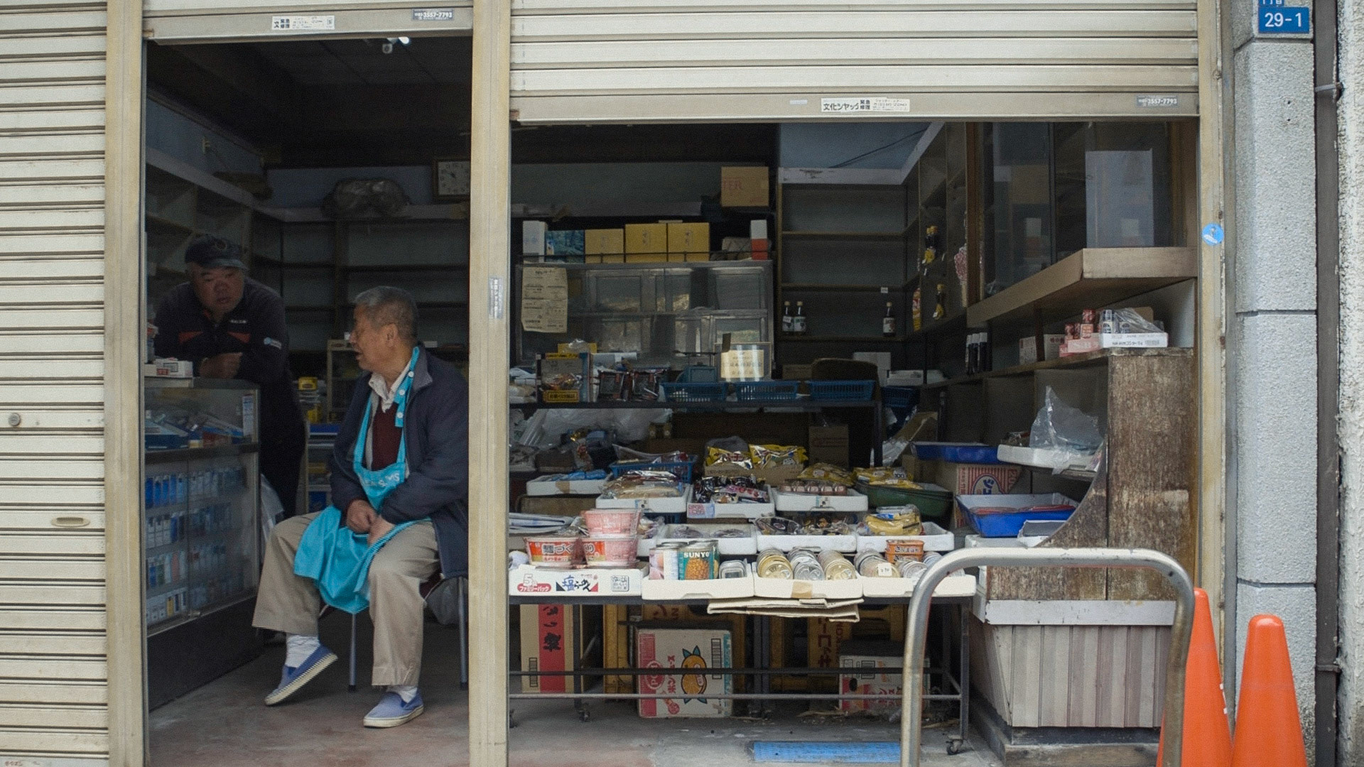 Harmonica 10 | Omi-ya, the shutter being closed halfway and selling limited items roughly arranged, is a local store in Sanya district where the owner has greeted and helped customers like Ishino by accepting a deffered payment and receiving a package for homeless people since 1922, 10 April 2020.
