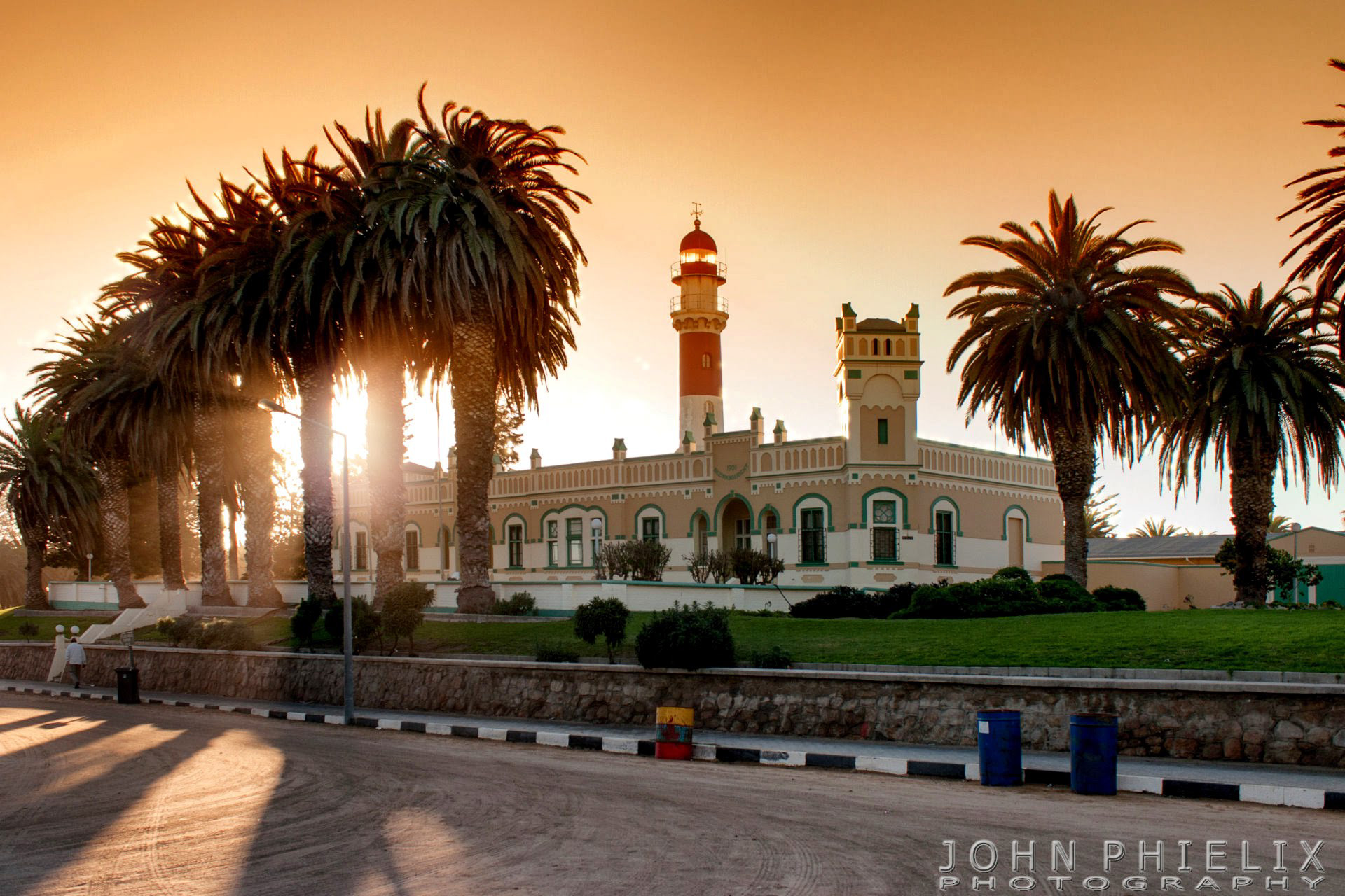 Swakopmund Lighthouse and adjacent colonial-era buildings framed by palm trees in Swakopmund, Namibia