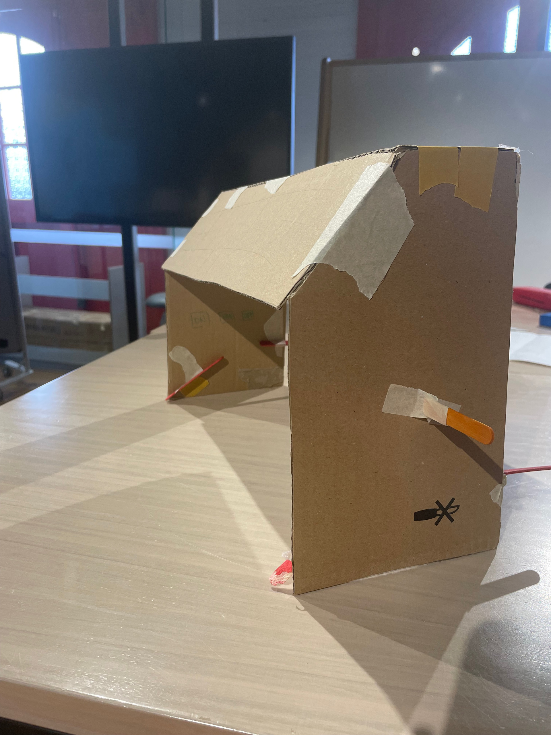 Universal Design in the Kitchen, Domestic Dough Sheeter Prototype. Created with cardboard, masking tape, popsticks and paper. Three-quarter side view, front.