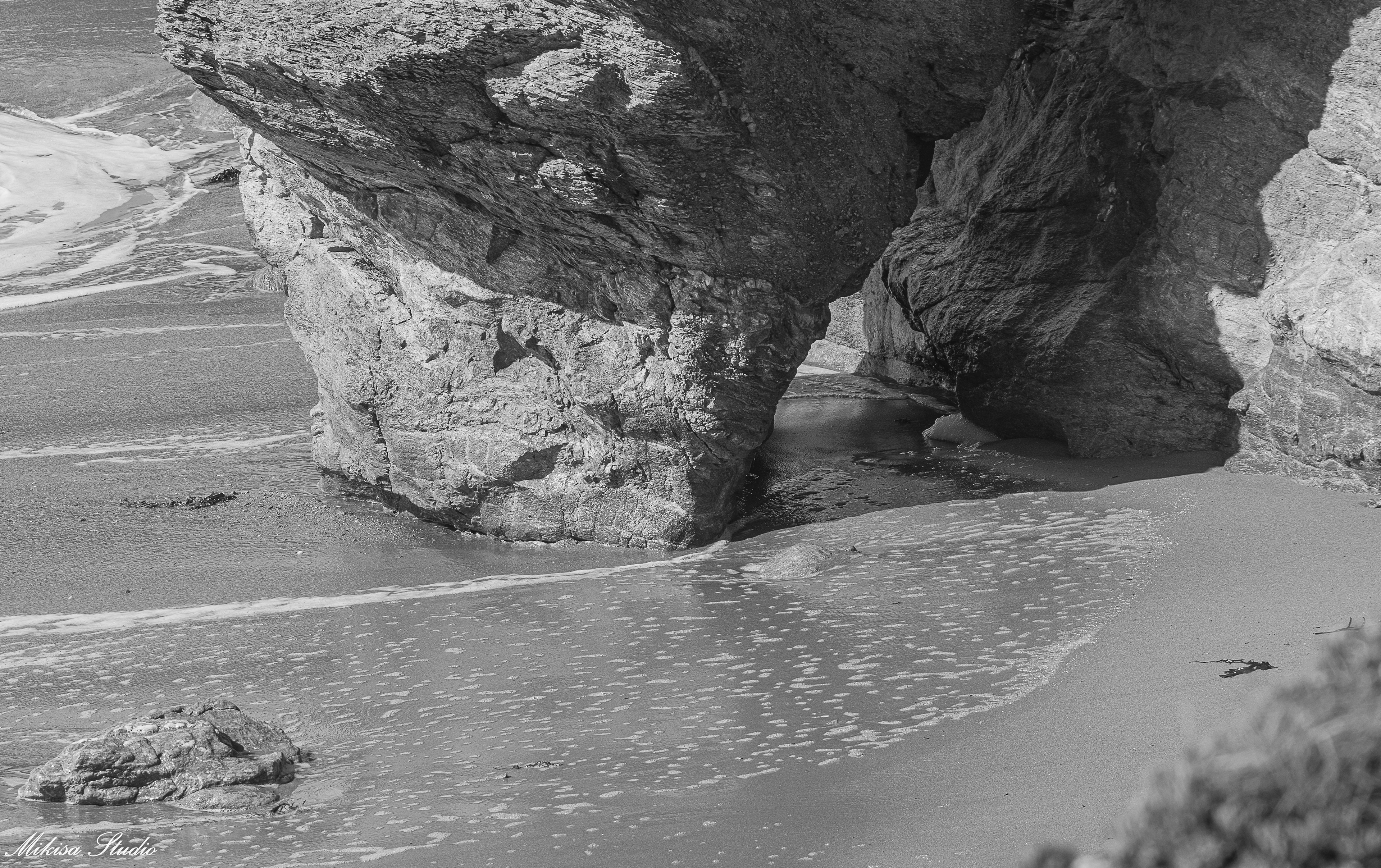 L'océan remonte au pied d'un rocher formant un passage autour de lui, photo noir et blanc 88