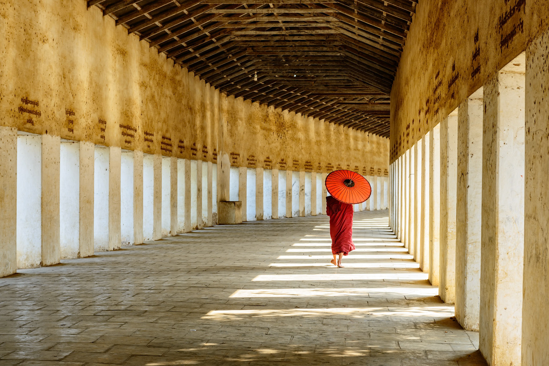 A young monk walks through the temple. A contrast of lines and color.