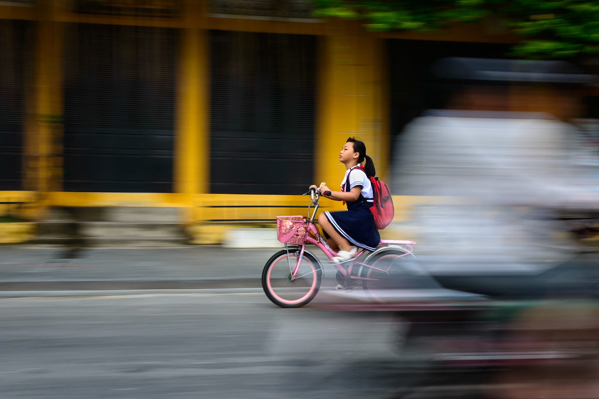 Practicing my panning shots, I saw this young girl pedaling fiercely along the road in Hoi An. I loved the outfit, the bicycle and the intensity of her efforts. As I clicked the shot another cyclist passed in front. I thought I'd missed it, but instead the other cyclist helped frame the shot and convey the speed of the young girl.