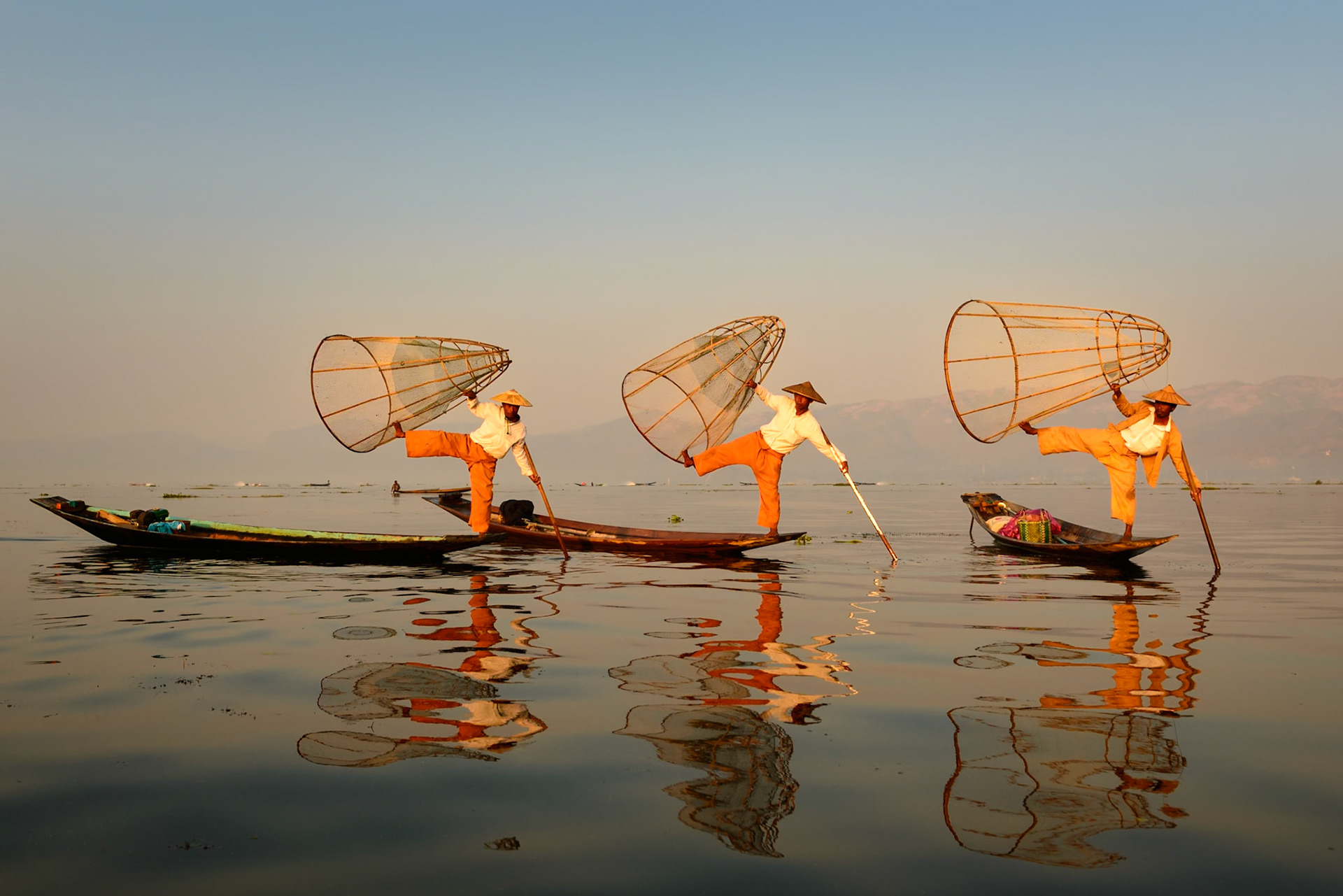 The light this  morning was a soft rich golden rose color and it lit up everything in a surreal fashion. Here three fisherman demonstrate their trade. Inle Lake, Myanmar