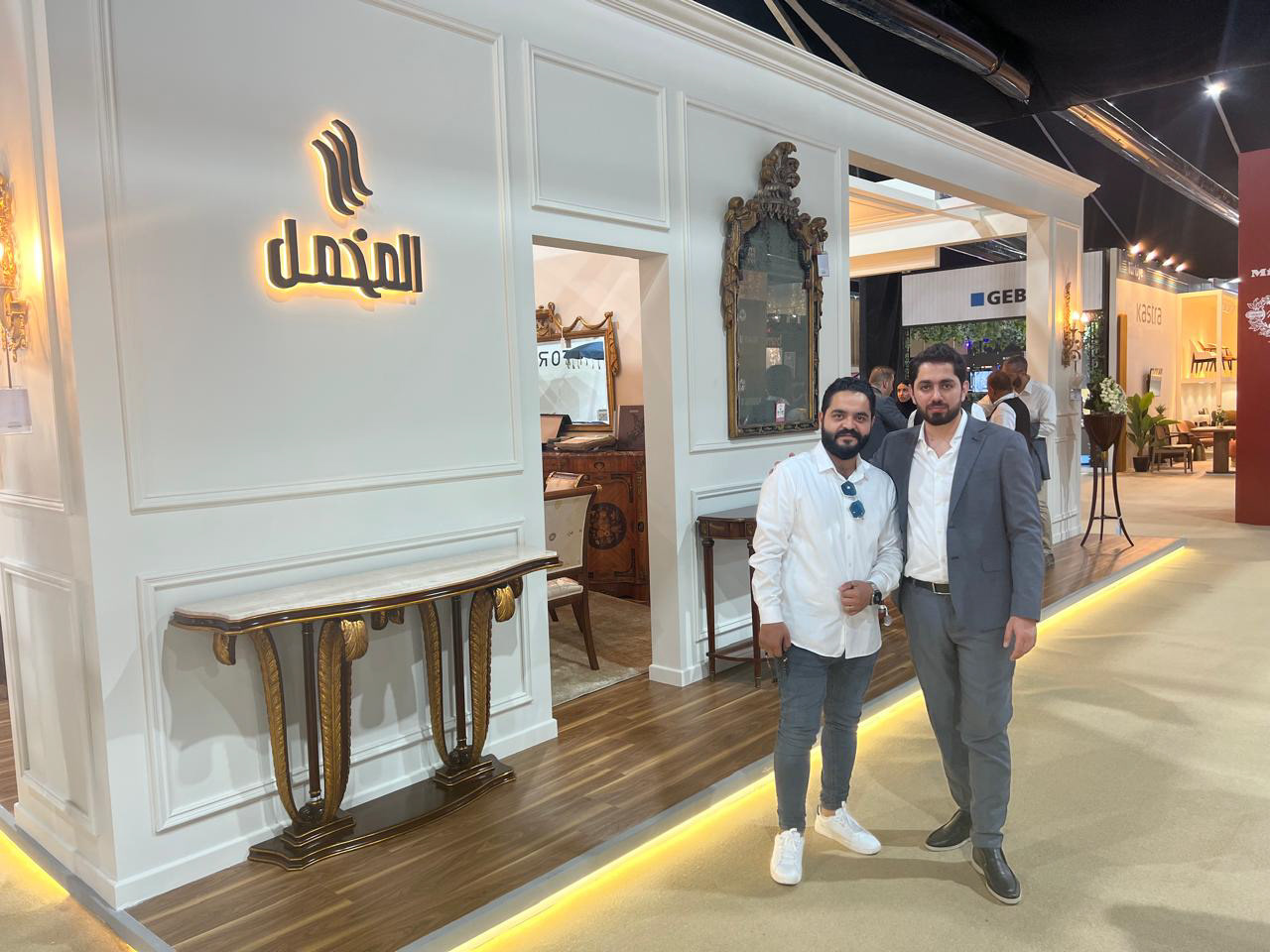 Behind view of the Al Mukmal booth with two of our supervisors, showcasing the coordination and organization that defines every aspect of the booth.