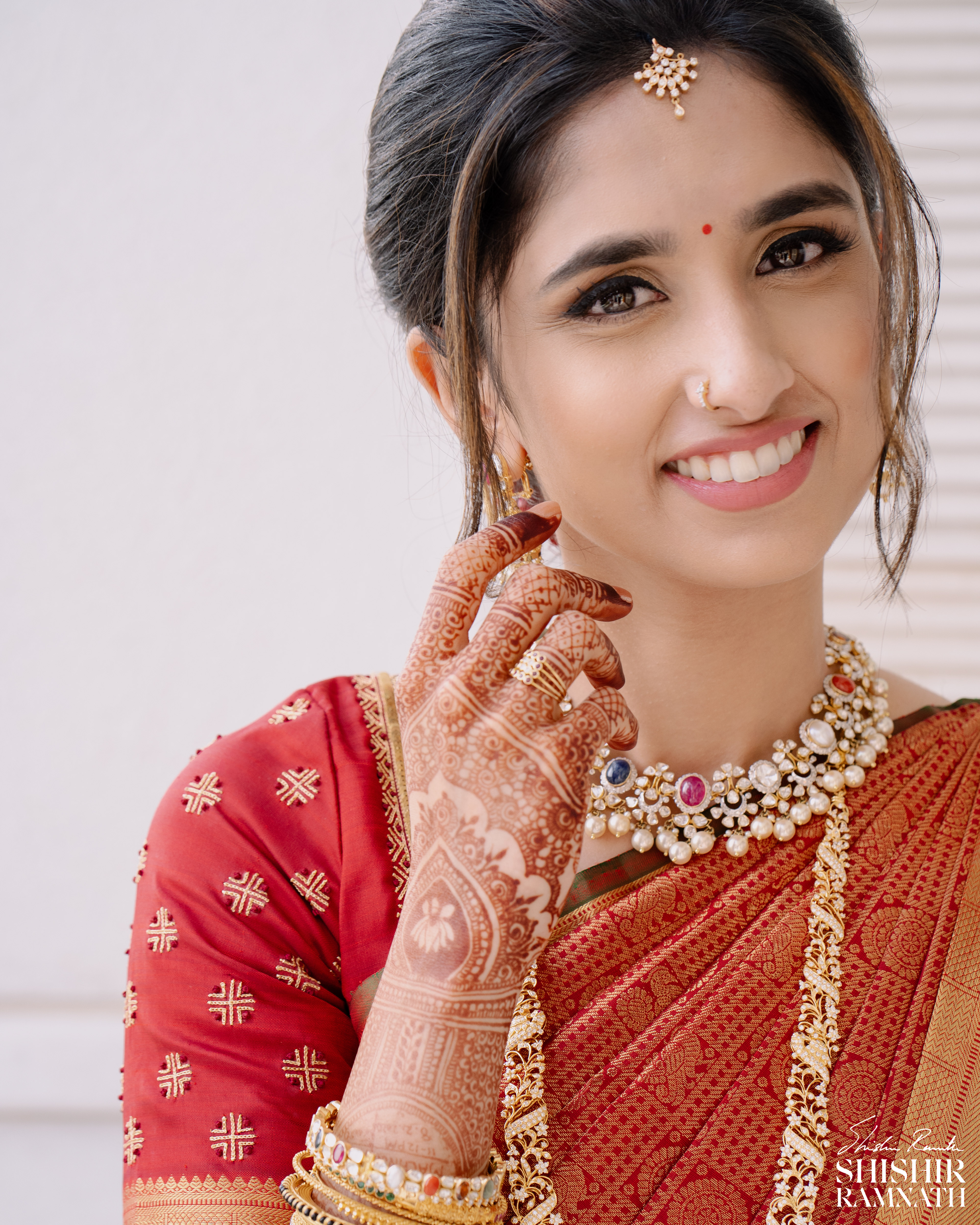 bridal portrait of a woman as she looks into the camera and smiles gracefully while shoeing her jewelery