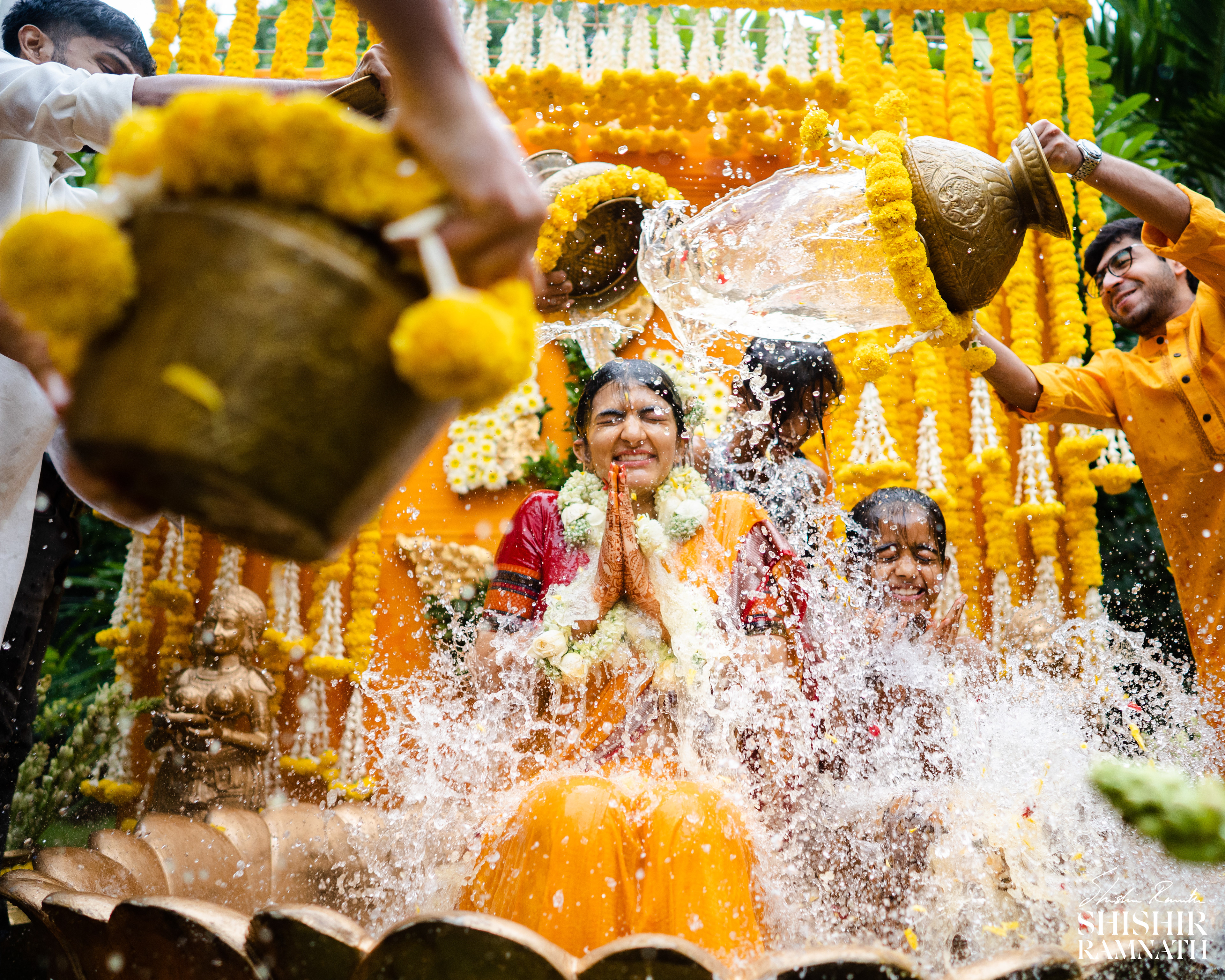  water falling on an indian bride fom all directions during her haldi ceremony