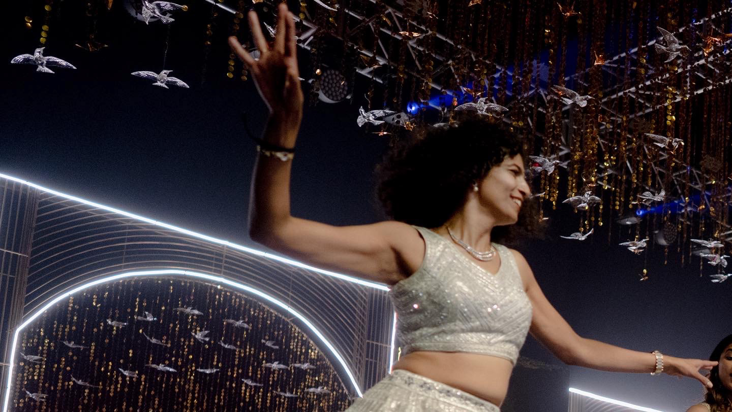 glass birds adorn the massive stage at a wedding in hyderabad with a bridesmaid dancing in front of it.