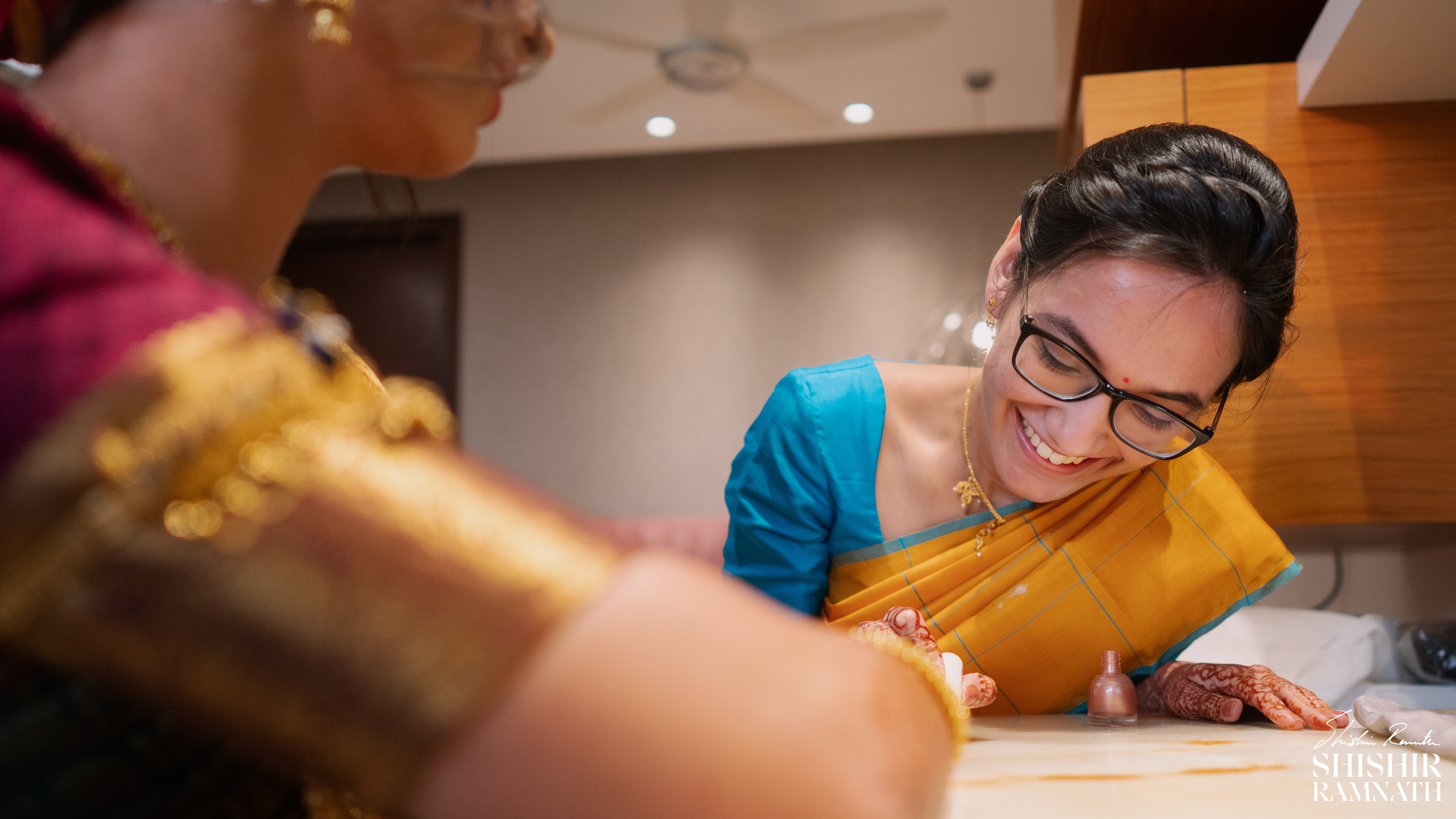 the brides cousin applies nail paint on the brides fingers and smiles at it